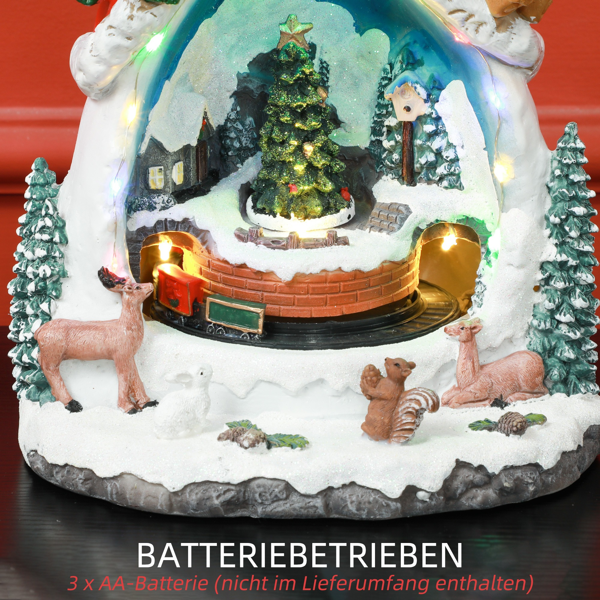 Eine detaillierte Ansicht der Weihnachtsdekoration mit Zug, Baum, Hirschen und Eichhörnchen in einer Schneekugel.