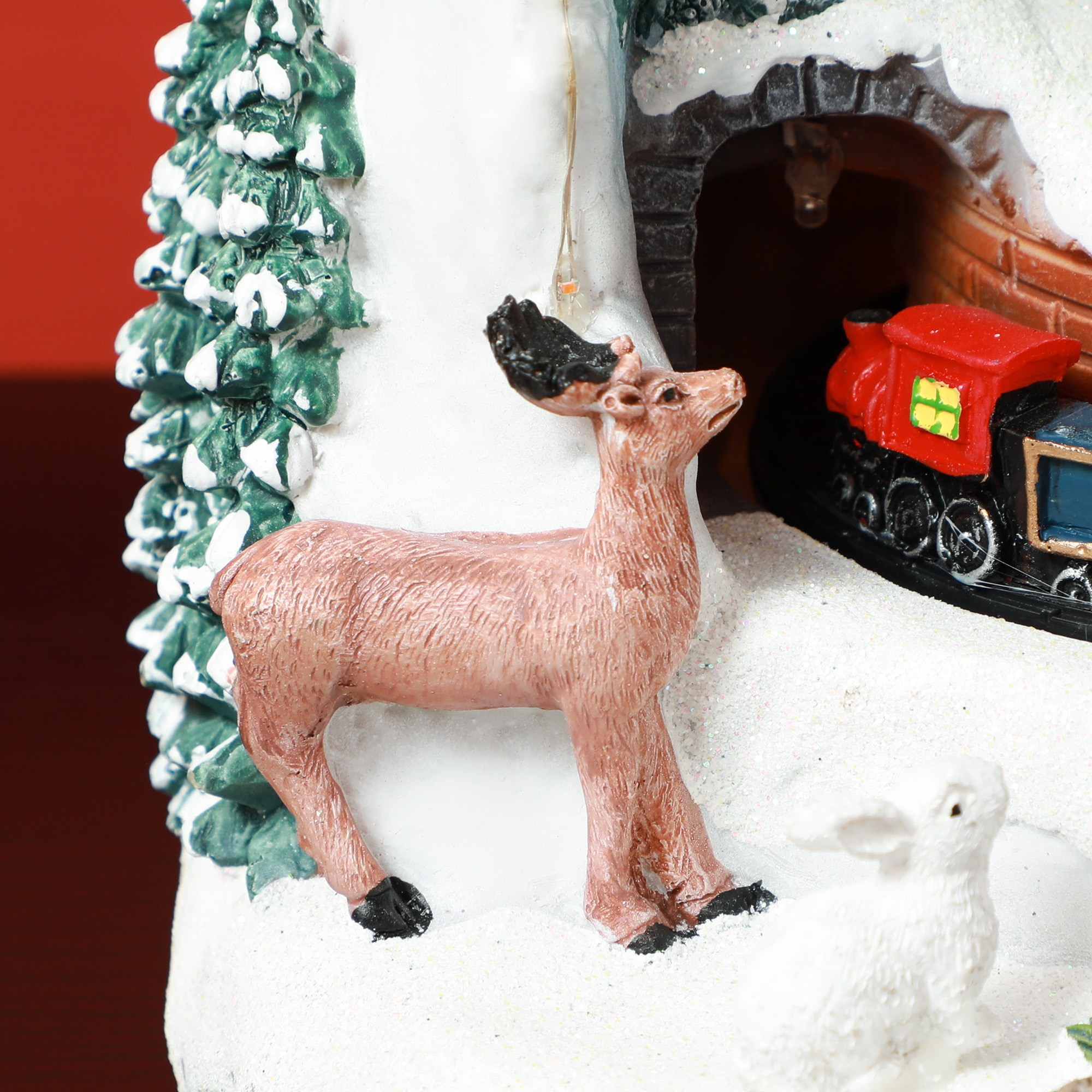 Nahaufnahme einer Rentierfigur in der Nähe einer verschneiten Zugszene mit einem Zug.