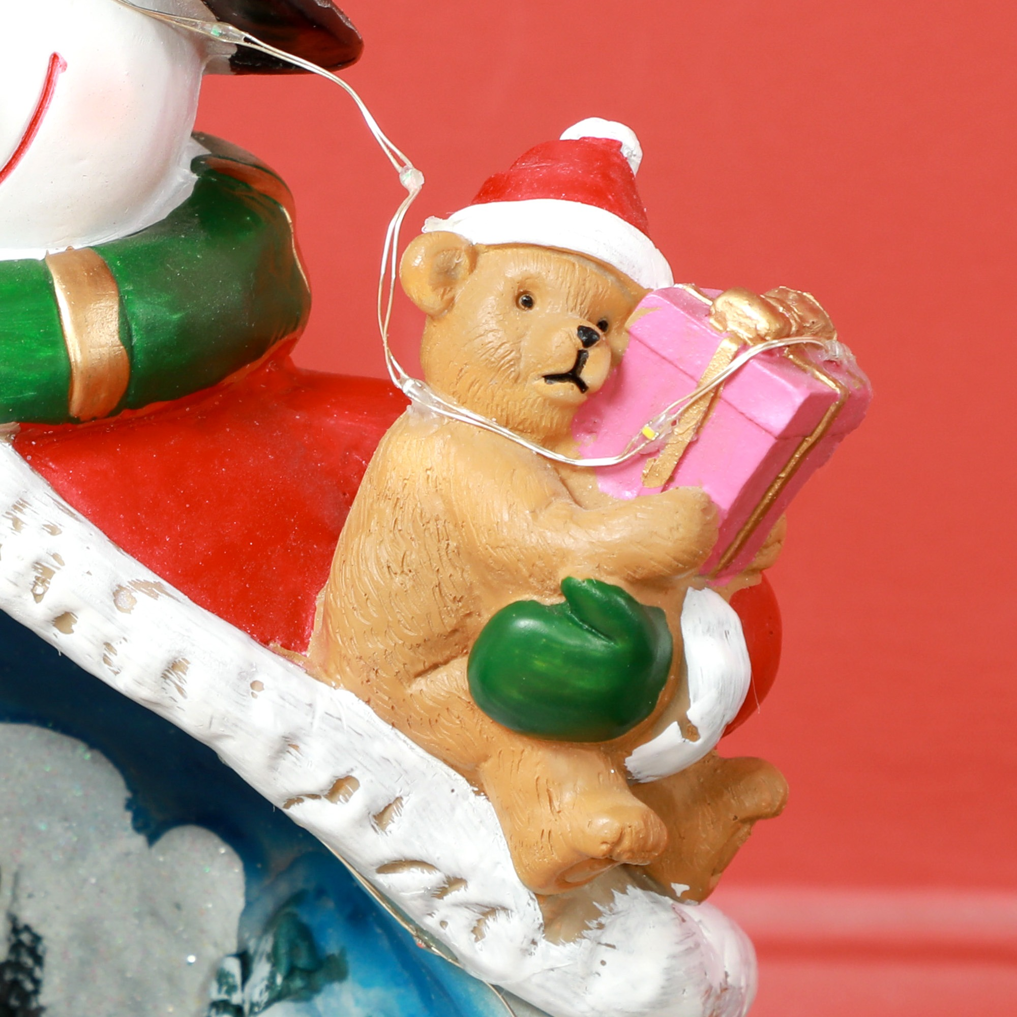 Ein Teddybär mit Weihnachtsmütze hält ein rosa Geschenk.