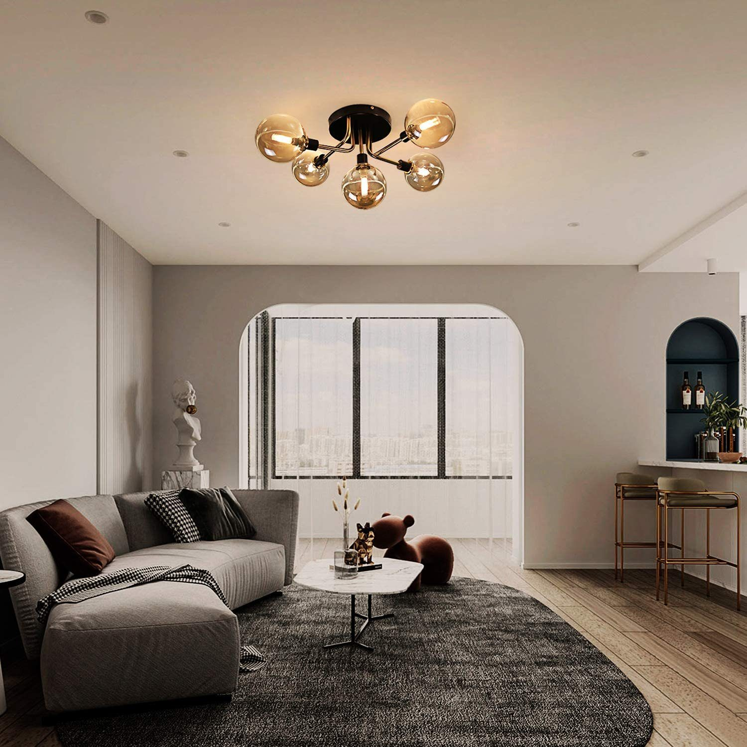 Deckenleuchte mit fünf bernsteinfarbenen Glaskugelleuchten. Wohnzimmer, weiße Wände, graues Sofa.