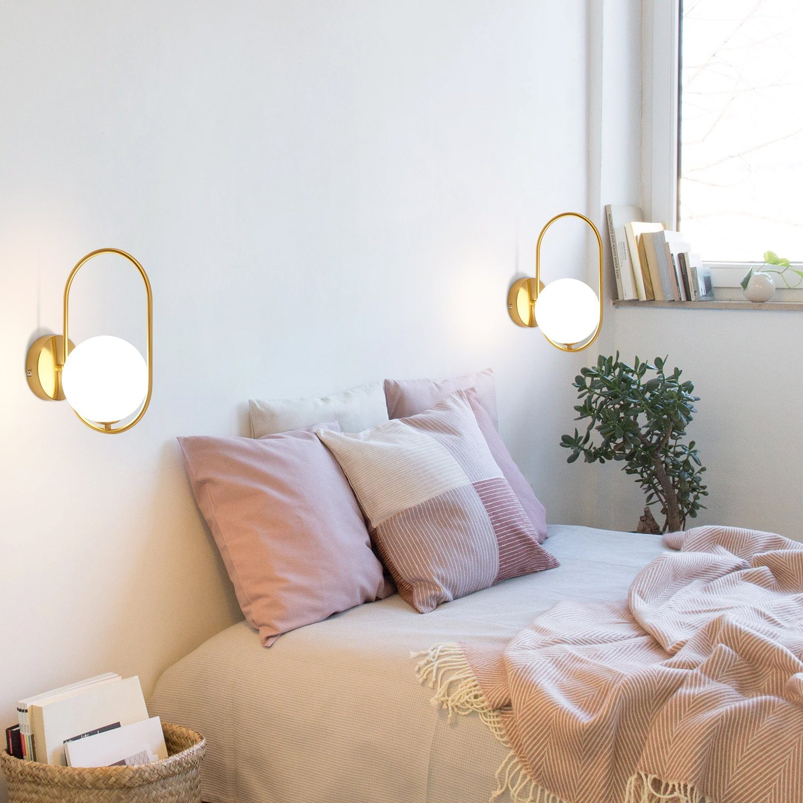Dos lámparas de pared con marco dorado y globo blanco. Ambiente de dormitorio.