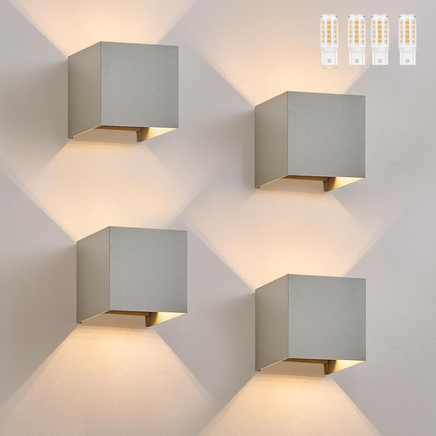Quattro luci da parete grigie a forma di cubo che emettono luce calda, con lampadine aggiuntive.