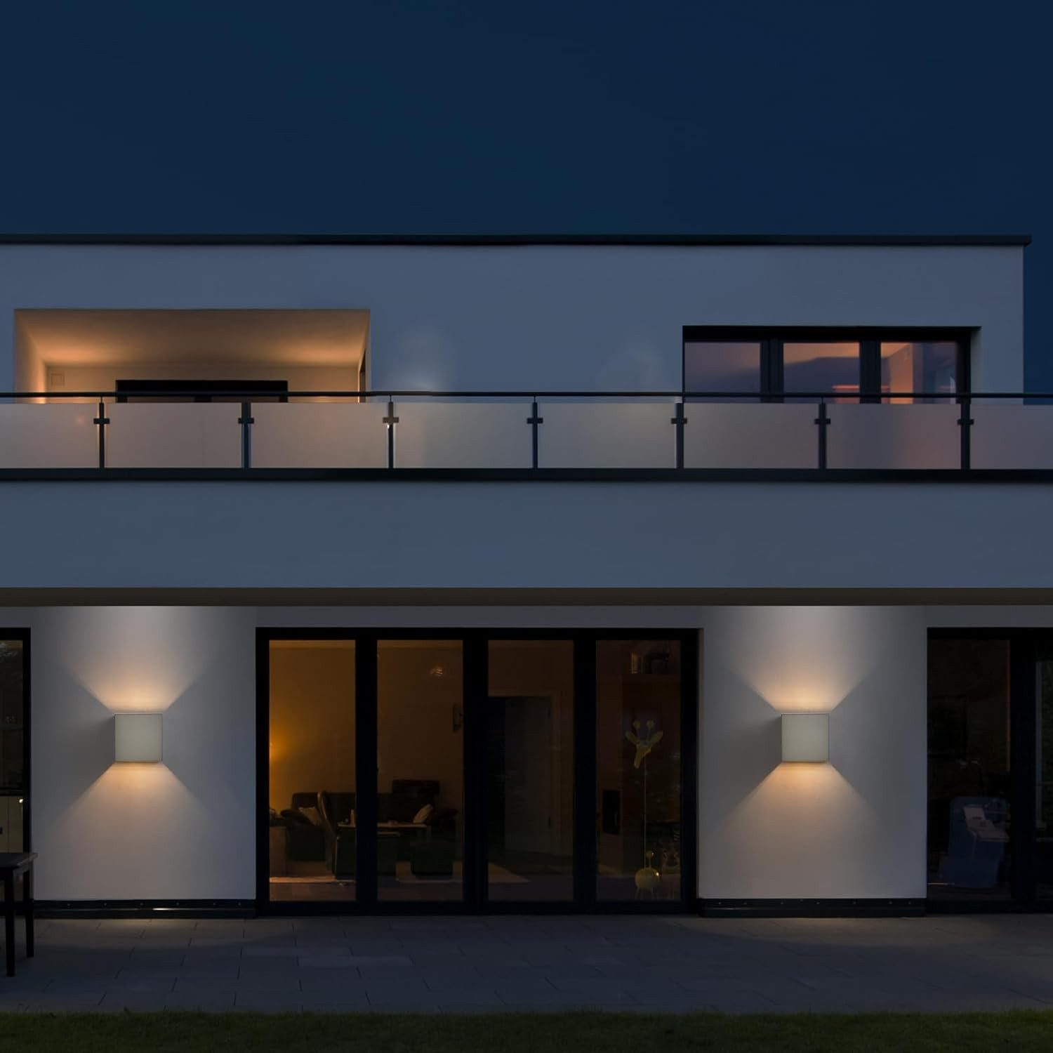 Esterno di una casa moderna di notte, illuminato da luci quadrate a parete.