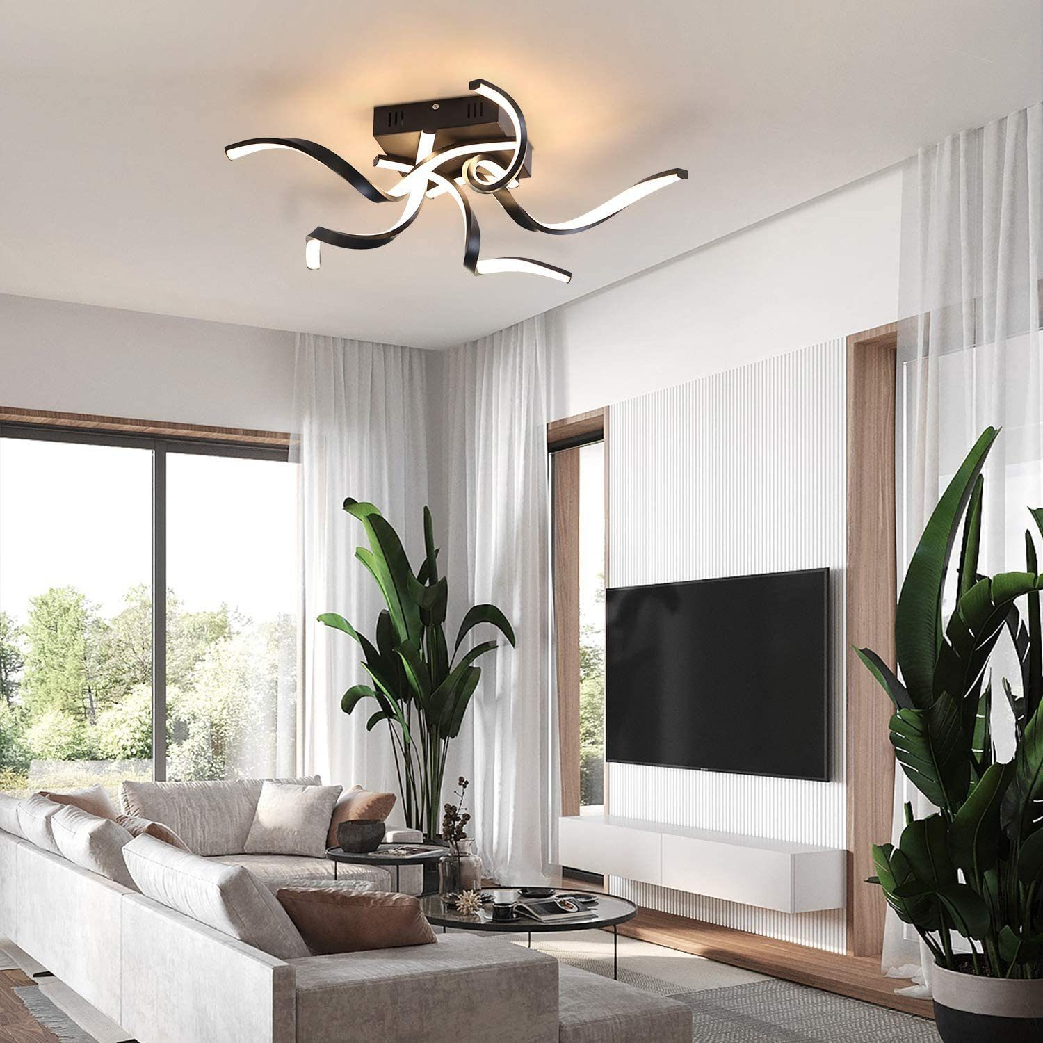 Wohnzimmer mit moderner Deckenleuchte, Sofa, Pflanzen und großem Fenster.