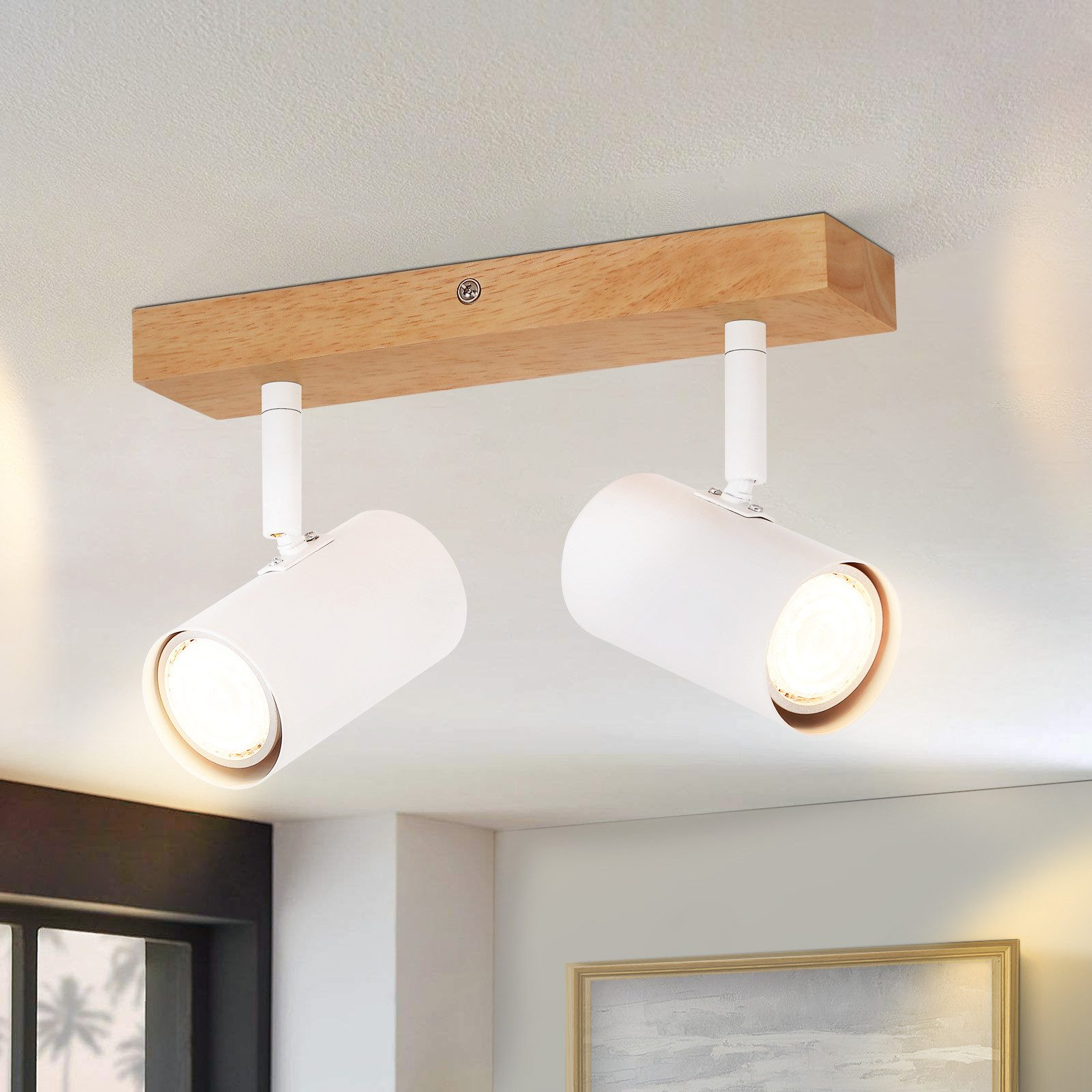 Due faretti bianchi montati su una trave di legno, posti su un soffitto.