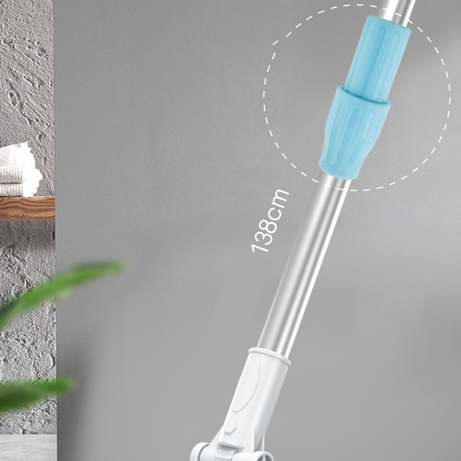 Wischmopp mit verstellbarem blauen Griff. Der Hintergrund ist eine graue Wand.