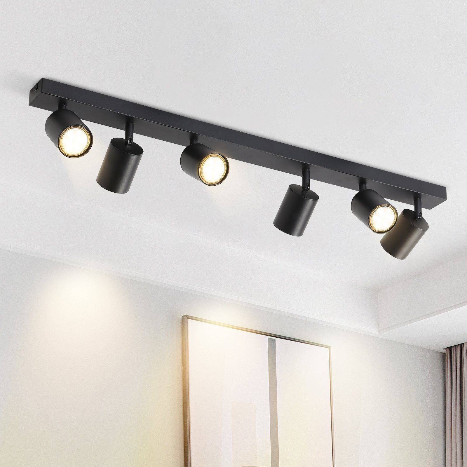 Faretti a soffitto montati su binario nero, che illuminano uno sfondo bianco.