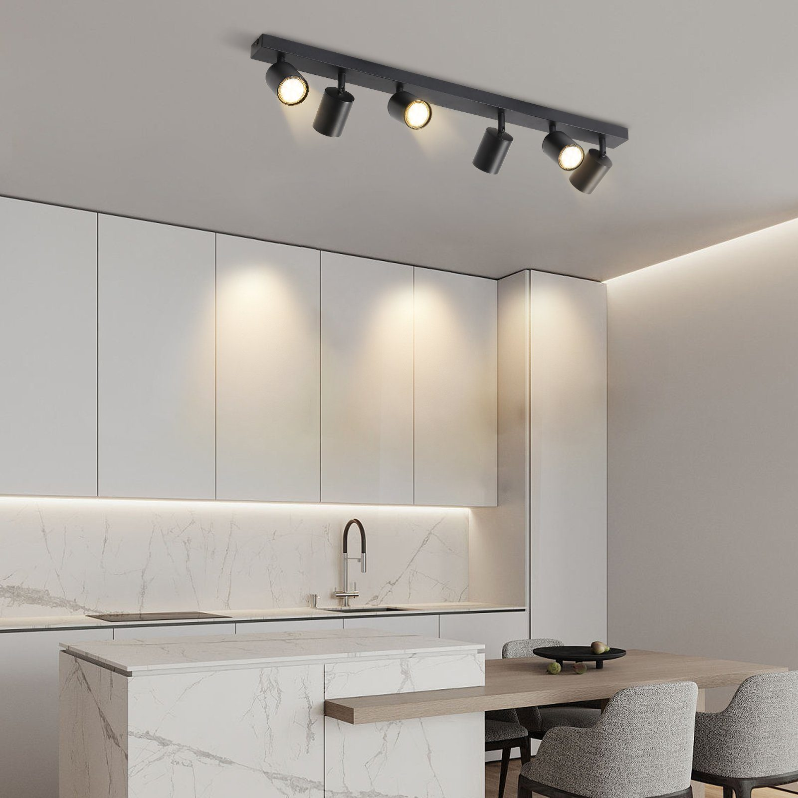 Una cucina con mobili bianchi, un tavolo in legno e un'illuminazione a binario con faretti.