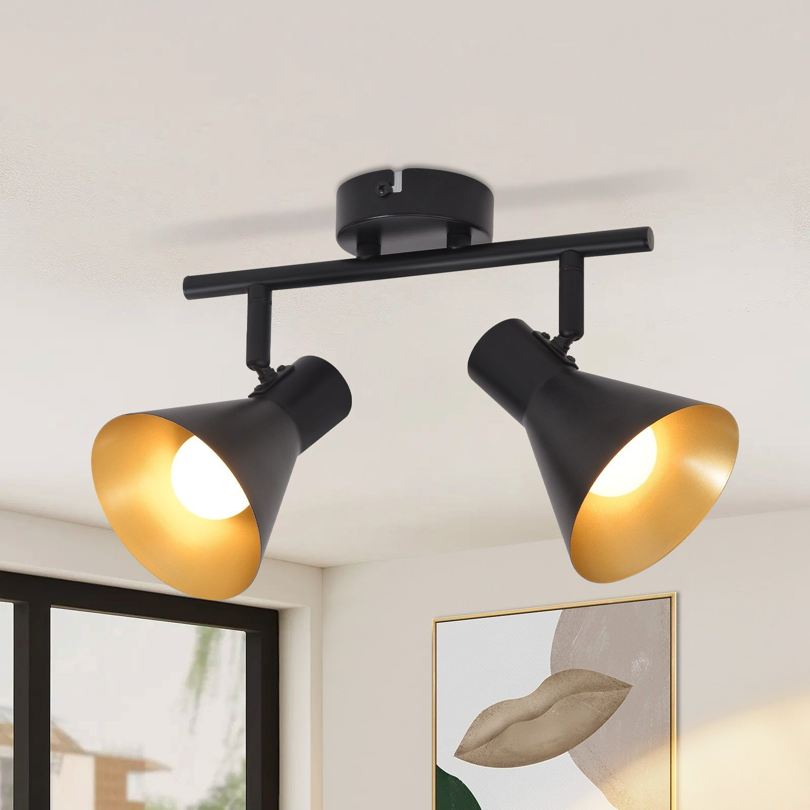 Due faretti neri su un soffitto bianco con un dipinto sullo sfondo. Luci accese.