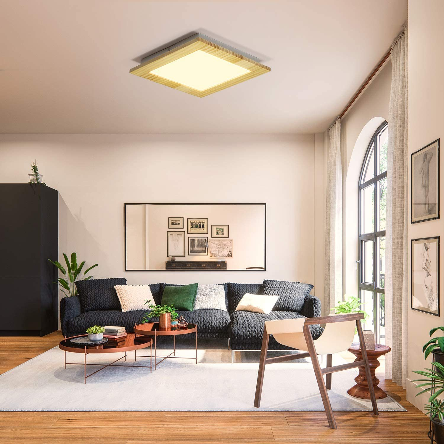 Ein Wohnzimmer mit einer quadratischen Deckenleuchte. Es hat ein Sofa, Stühle und einen großen Spiegel.
