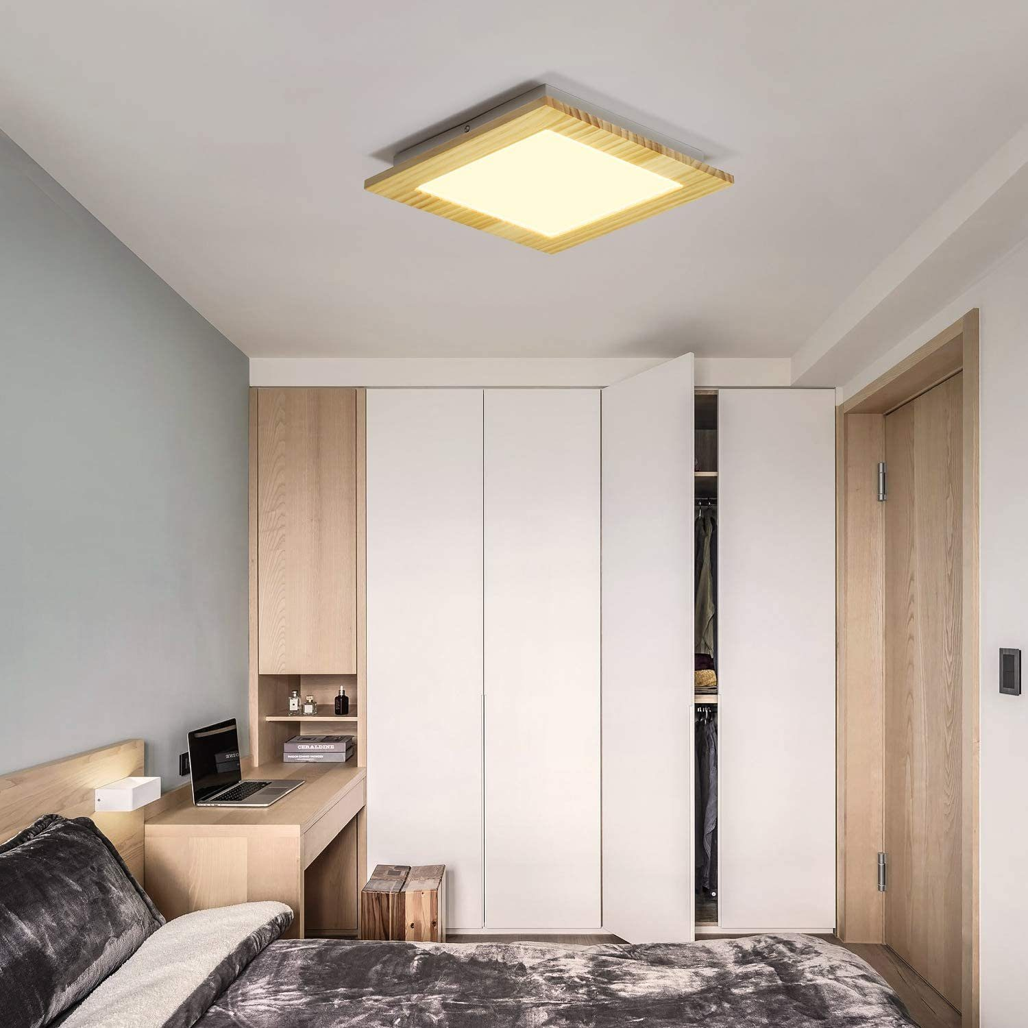 Schlafzimmer mit Deckenleuchte, Schreibtisch und Schrank. Helle Holztöne und neutrale Farben.