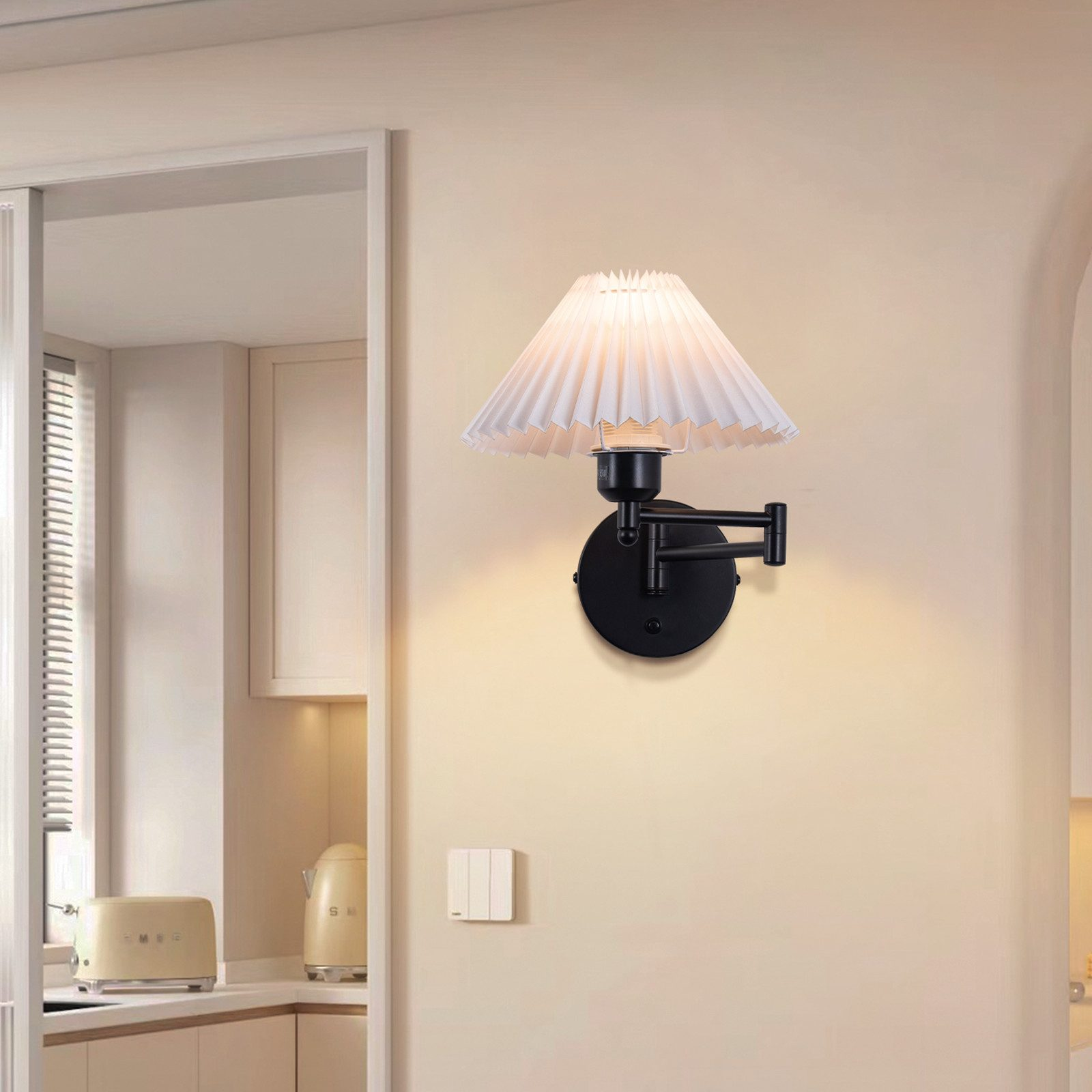 Una lampada da parete con un paralume bianco. La lampada è nera e lo sfondo è una cucina.