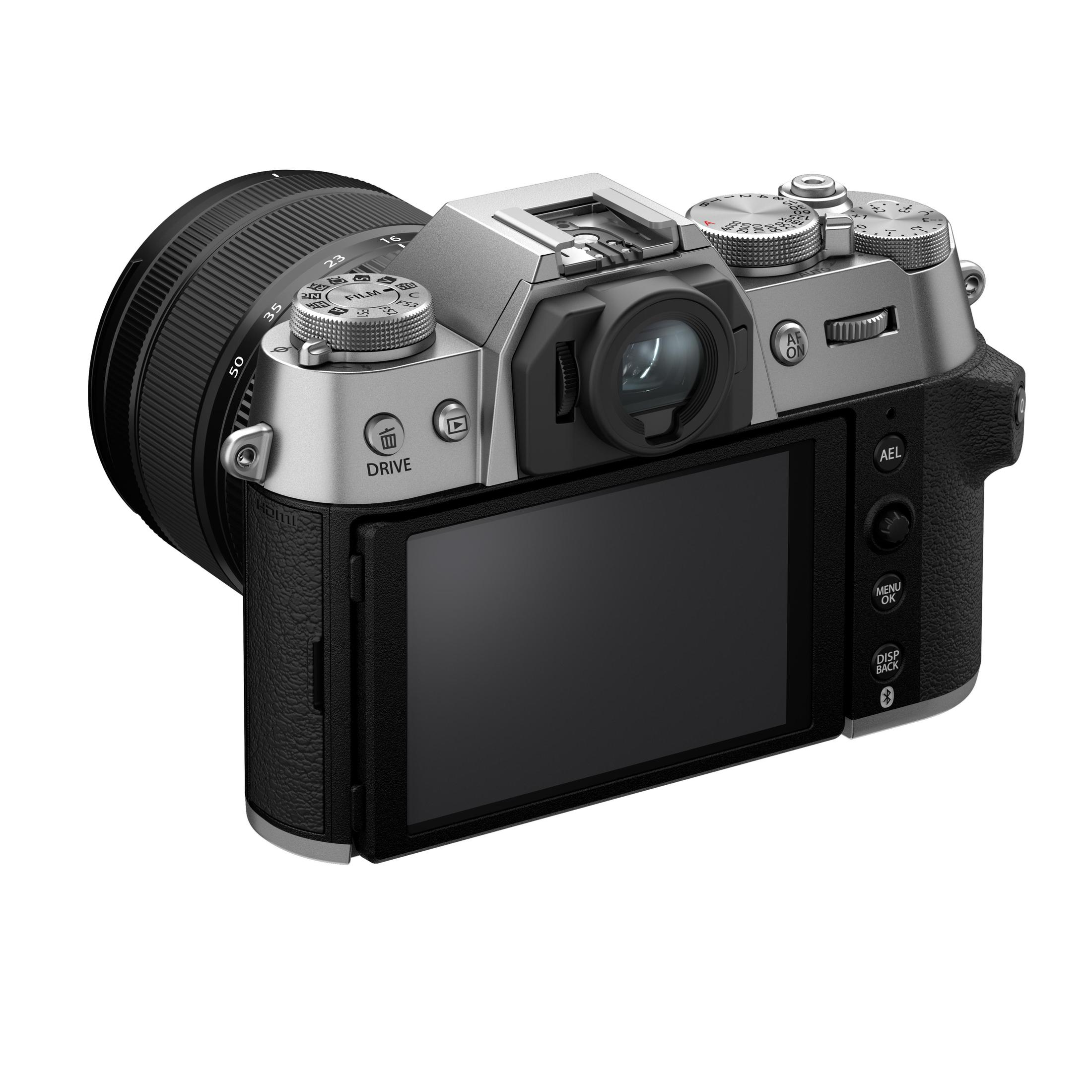 Zilveren camera met een zwarte lens, schuin om het achterscherm te laten zien, knoppen en draaiknoppen zijn zichtbaar.