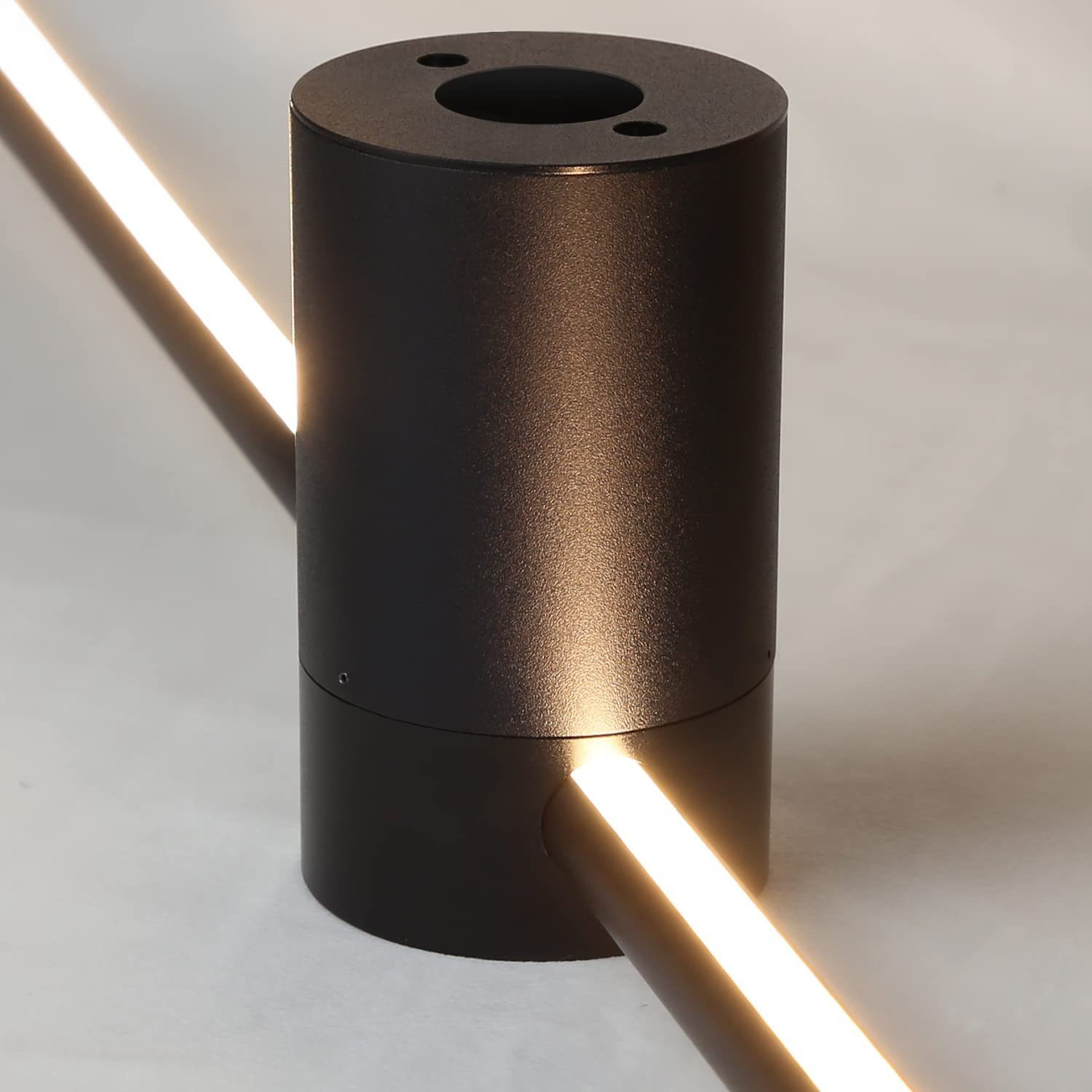 Un apparecchio di illuminazione cilindrico nero con una striscia di luce brillante. Lo sfondo è di colore neutro.