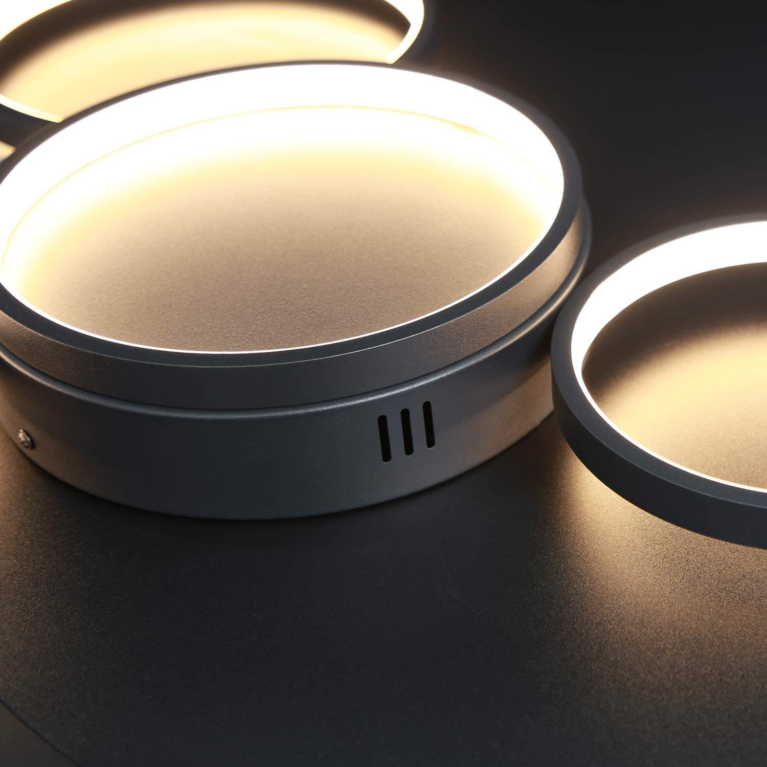 Nahaufnahme moderner Deckenleuchten mit kreisförmiger, heller LED-Beleuchtung und dunklem Hintergrund.