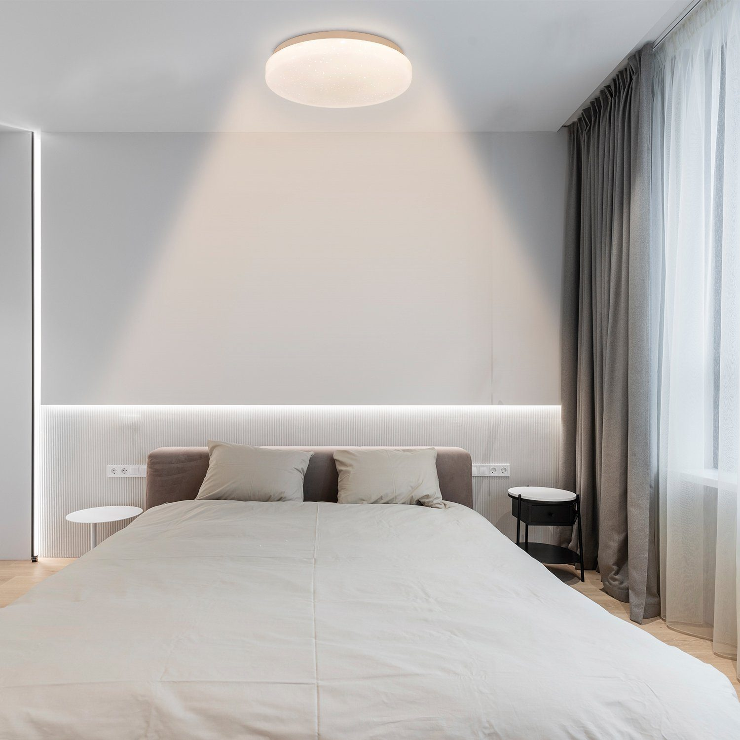Ein Schlafzimmer mit Bett, zwei Nachttischen und einer großen Deckenleuchte.