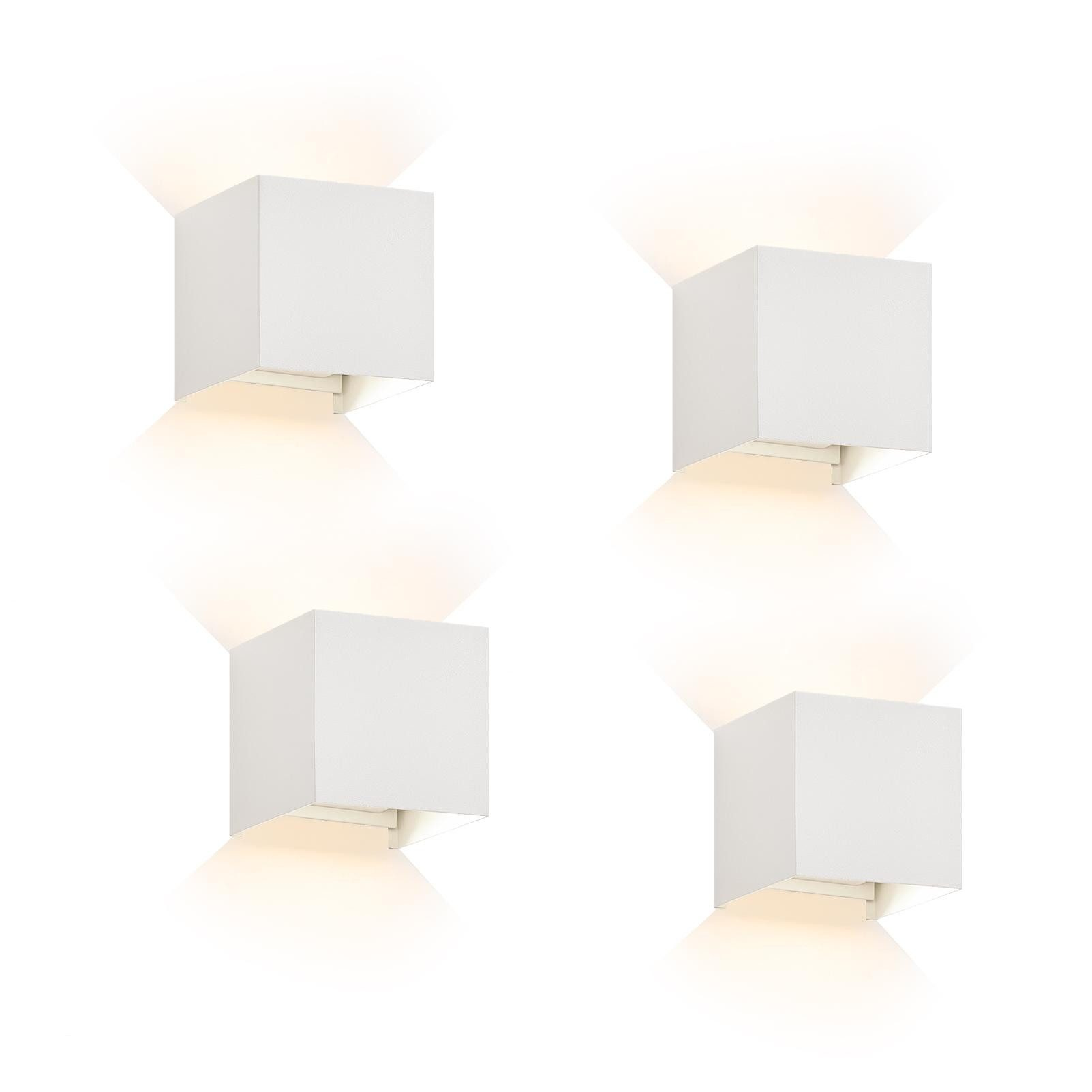 Quattro lampade da parete bianche a forma di cubo con un bagliore di luce soffusa che emana dal basso.