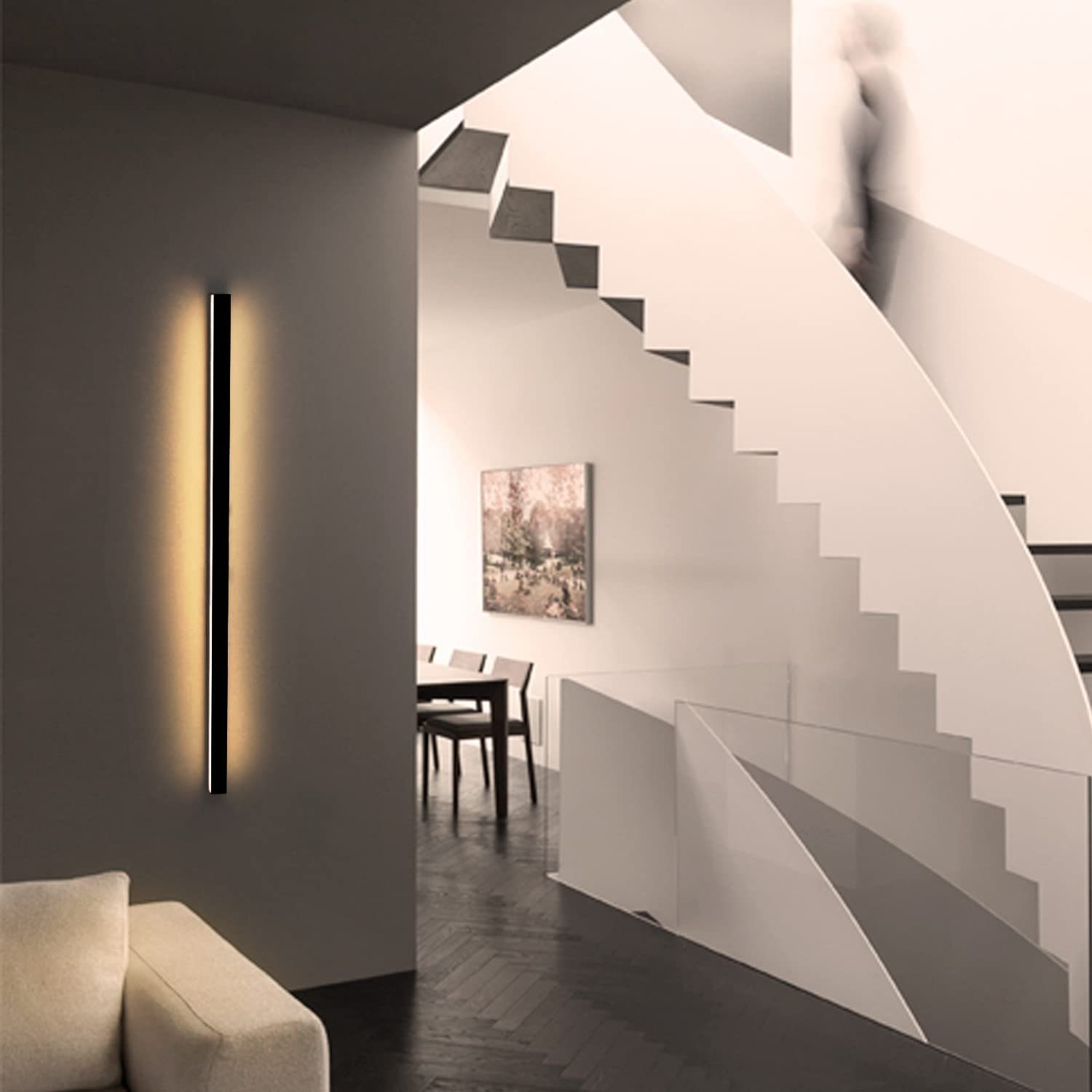 Eine Wand mit einer modernen schwarzen Leuchte und einer Treppe im Hintergrund.