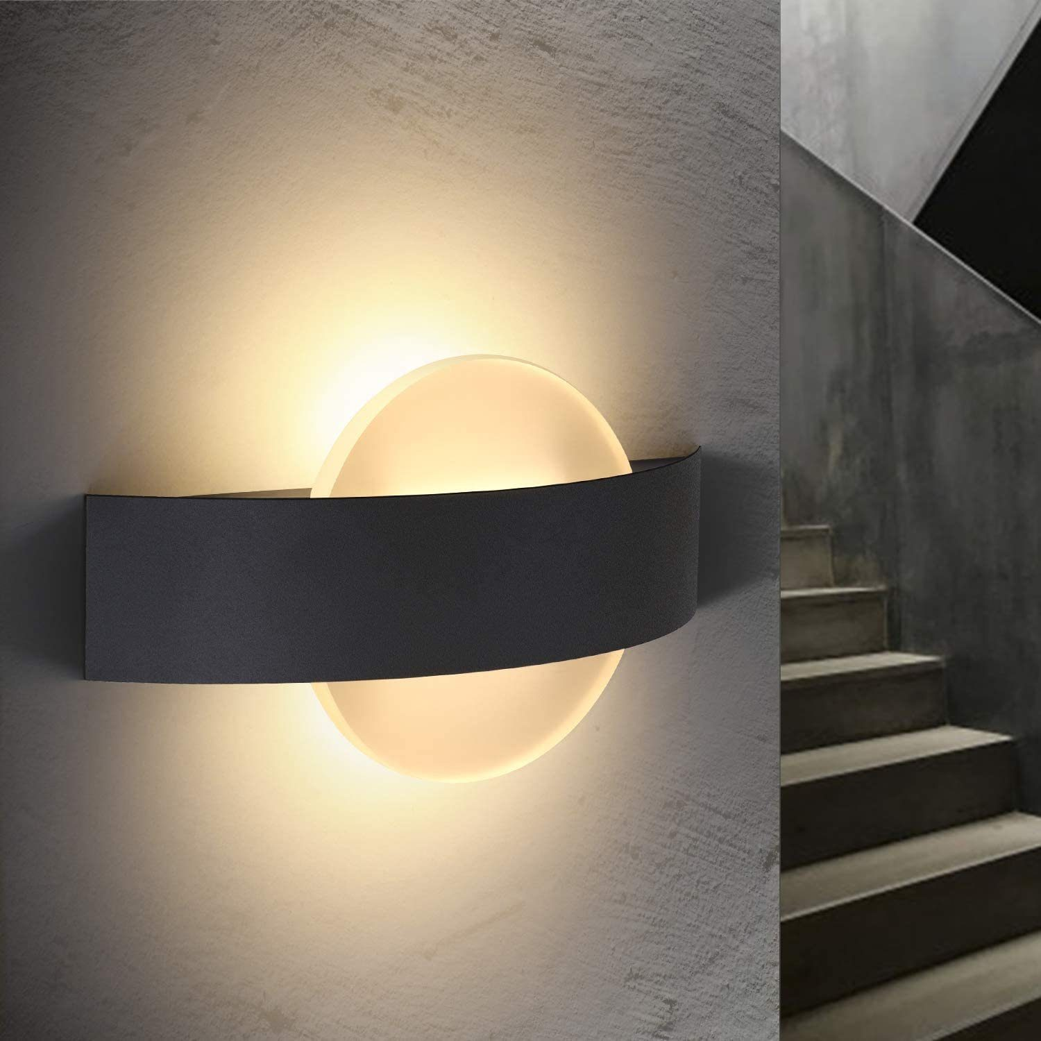 Czarna lampa ścienna z okrągłym światłem i szarym tłem ze schodami.
