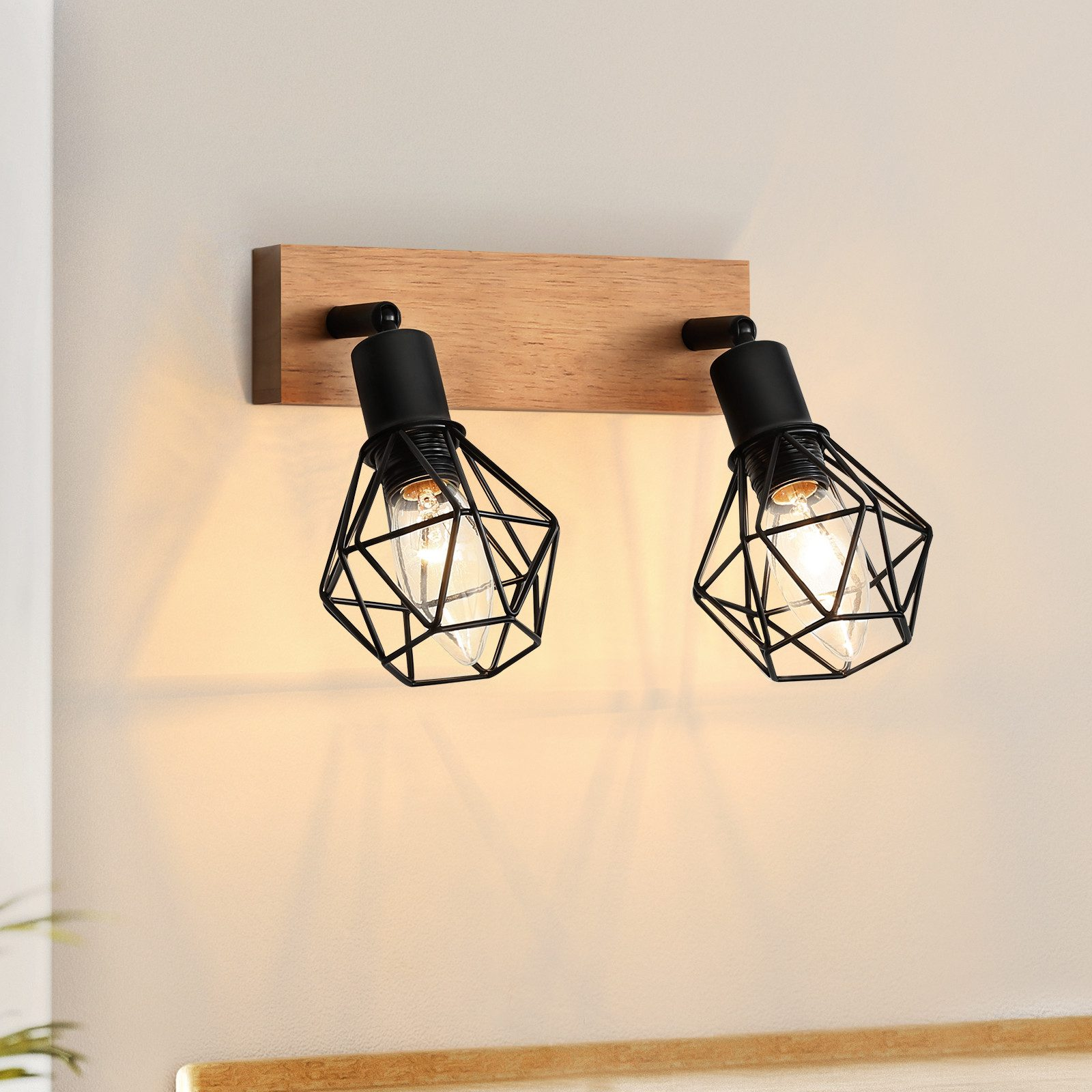 Due lampade nere con gabbie di filo su una tavola di legno. Muro sullo sfondo.