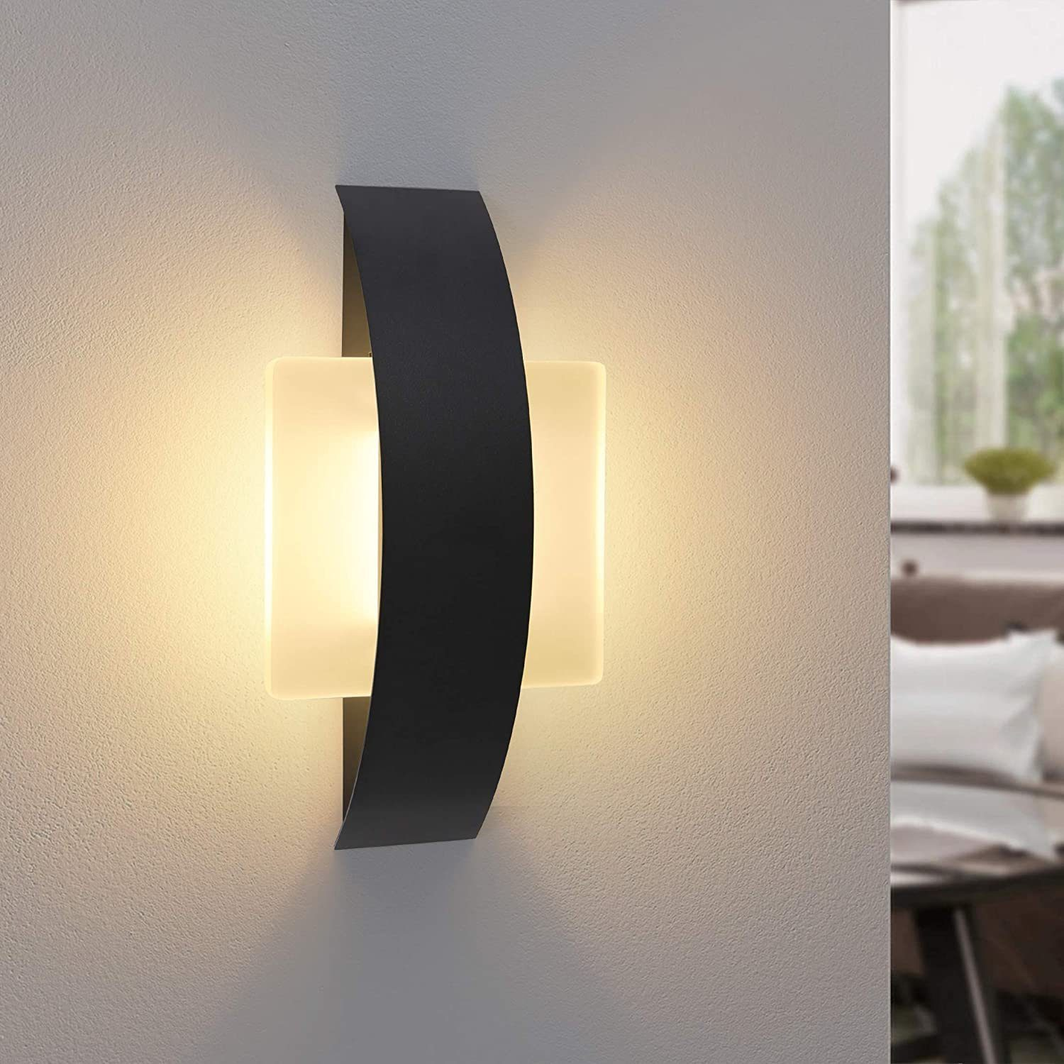 Una moderna lampada da parete con un design curvo nero e una sorgente luminosa rettangolare brillante.
