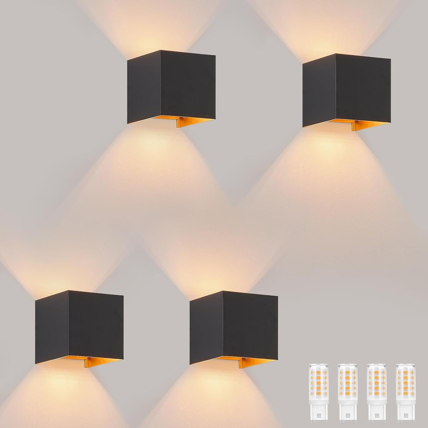 Quattro lampade da parete quadrate nere con interni dorati, che proiettano luce verso il basso e verso l'esterno.