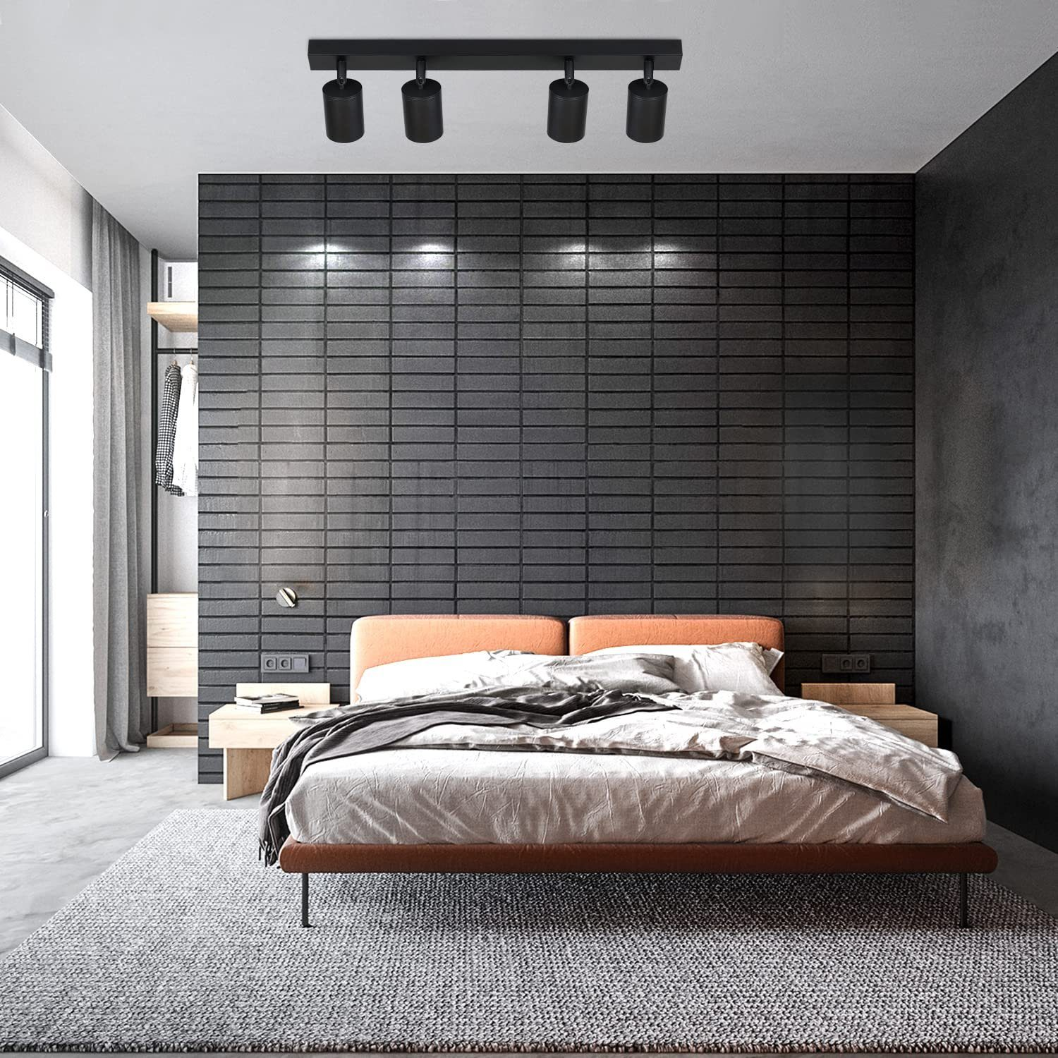 Sypialnia z łóżkiem, ciemną ceglaną ścianą i systemem oświetlenia szynowego z czterema reflektorami na suficie.