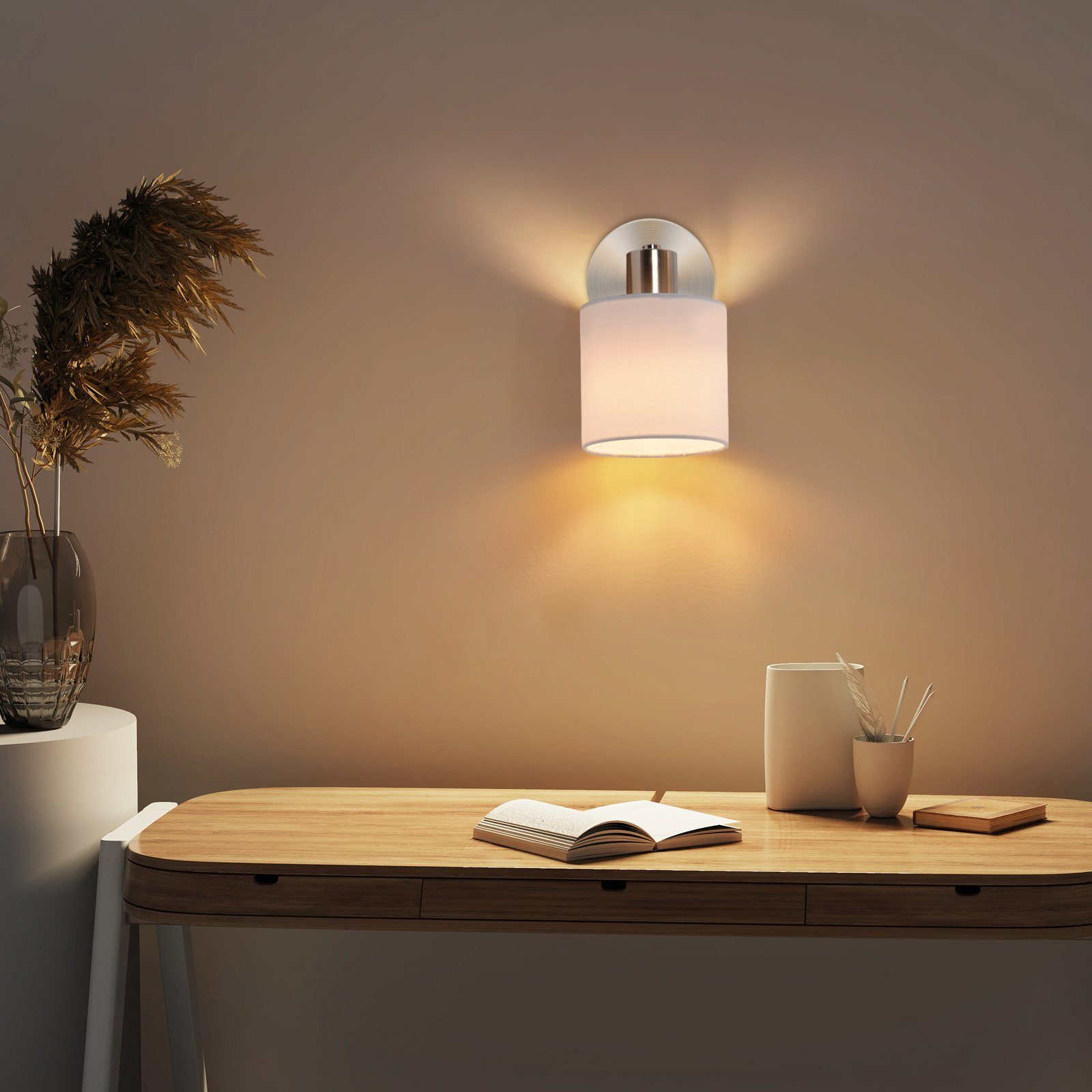 Una lampada su una scrivania, con un libro e oggetti, vicino a un muro.