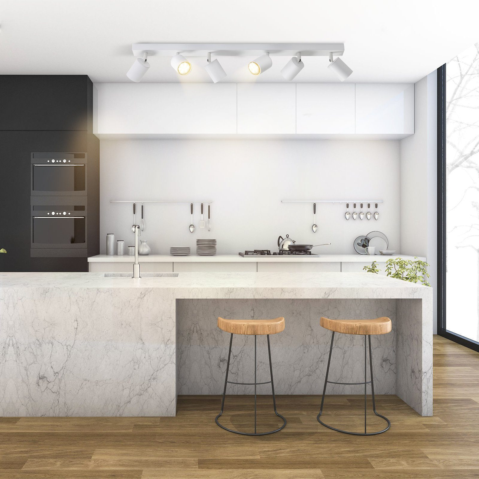 Cucina moderna con mobili bianchi, isola in marmo con sgabelli e illuminazione a binario bianca.