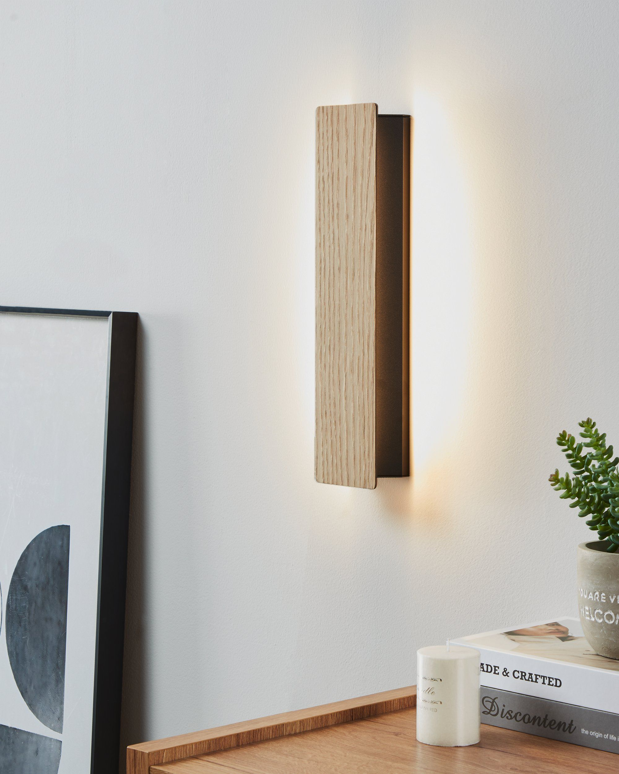 Moderne Wandleuchte mit Holz- und schwarzen Paneelen. Emittiert Licht an einer weißen Wand.