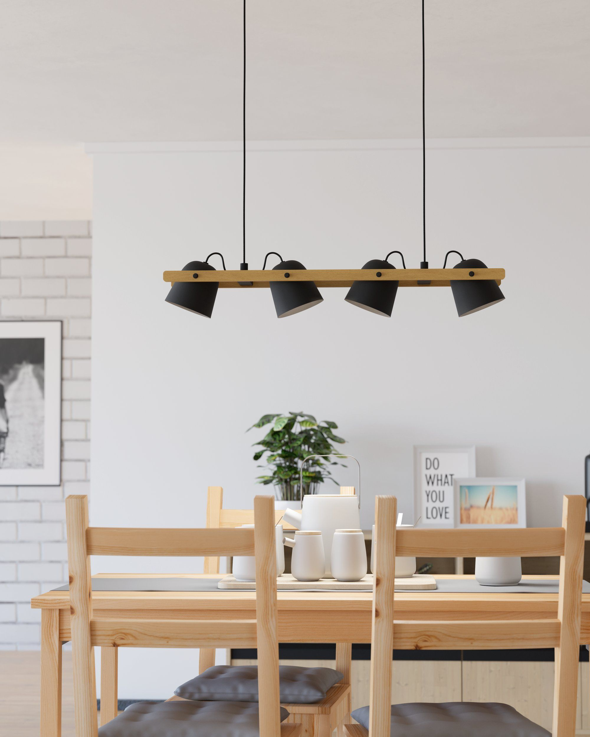 Vier schwarze Lampen an einem hellen Holzbalken, über einem Esstisch aufgehängt. Weiße Wand, Rahmen und Deko im Hintergrund.