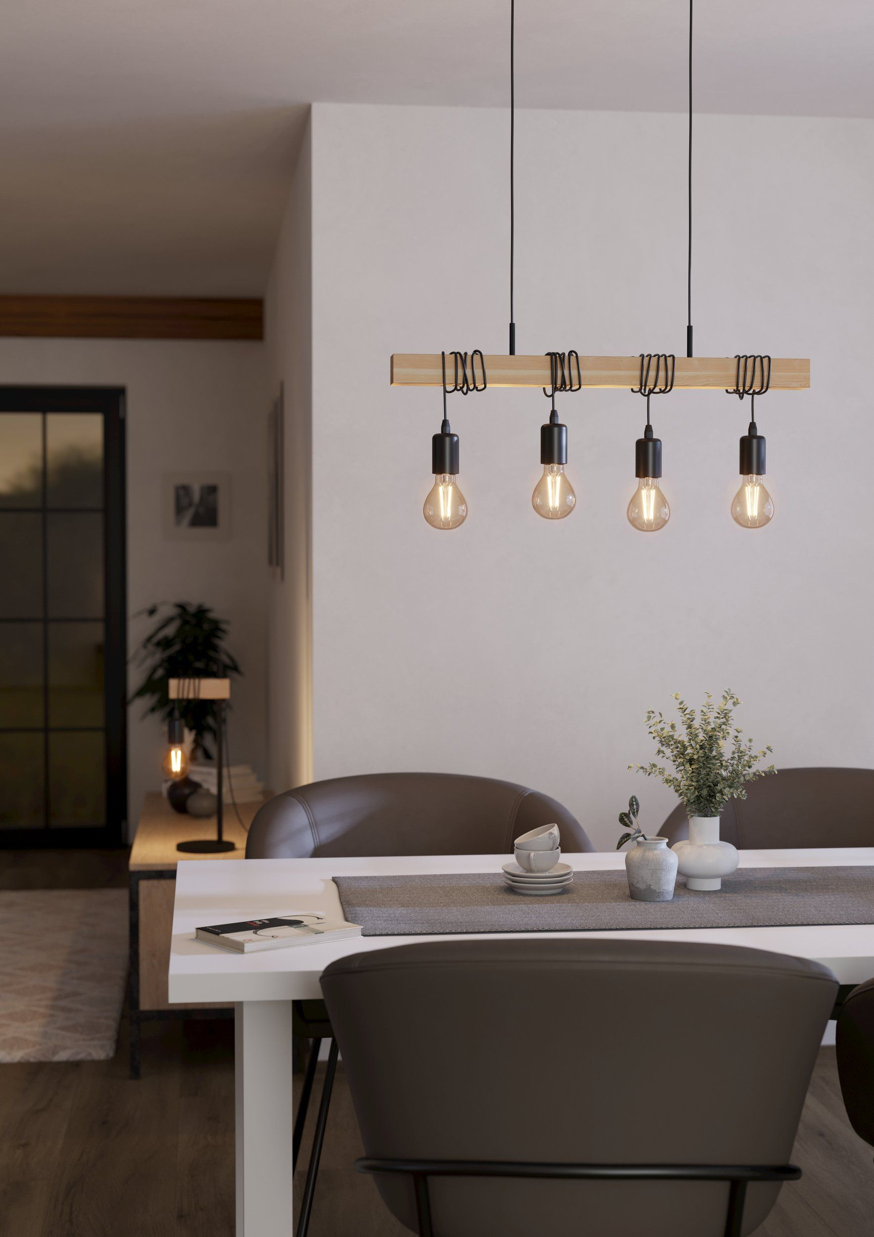 Una sala da pranzo con un lampadario a trave di legno. Il lampadario pende sopra un tavolo bianco.