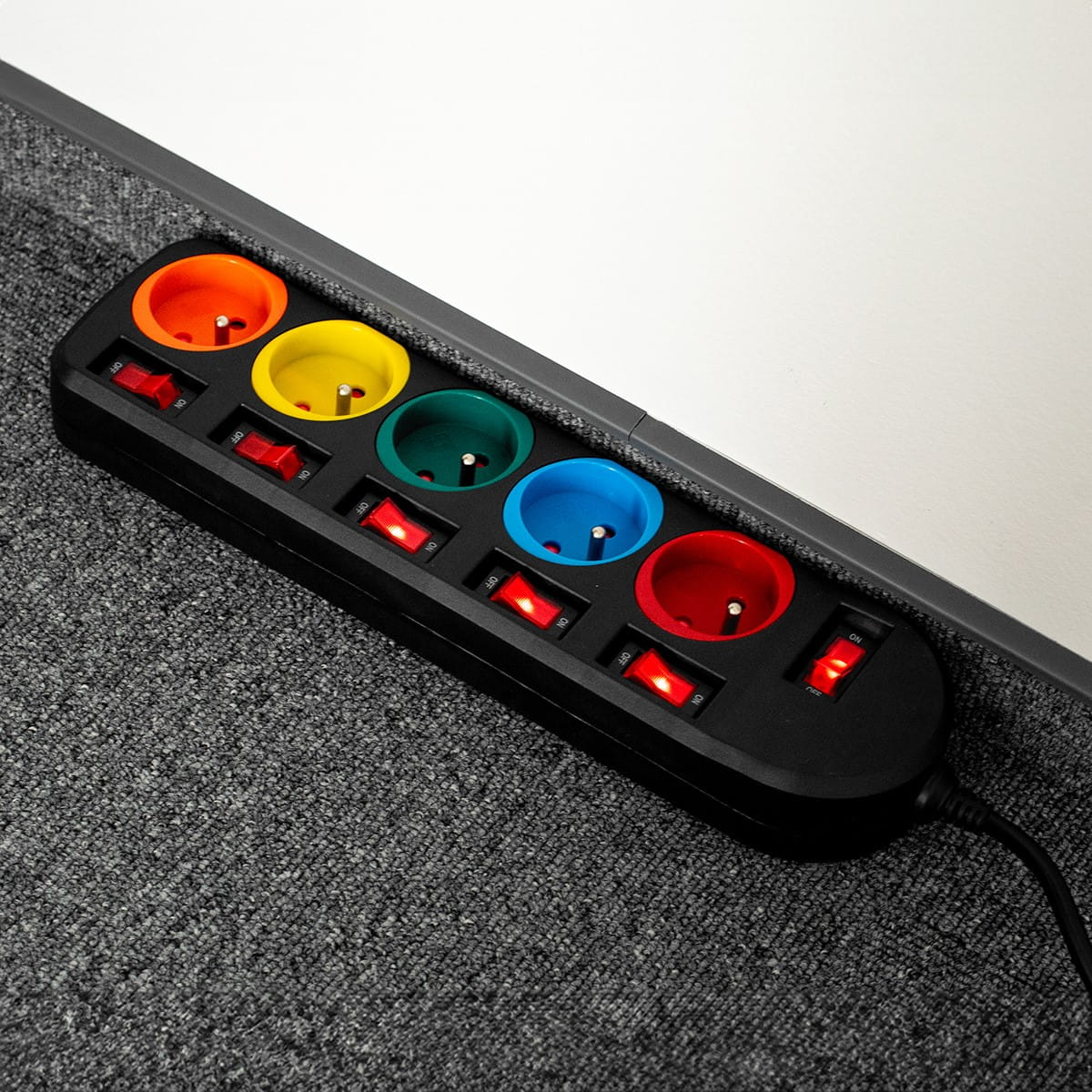 Czarna listwa zasilająca z pięcioma gniazdami w różnych kolorach i indywidualnymi podświetlanymi przełącznikami.
