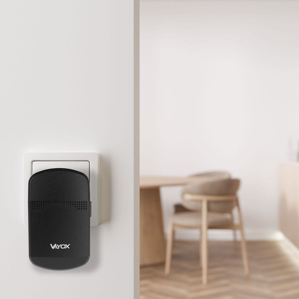 Czarny nadajnik dzwonka Vayox wpięty w białe gniazdo ścienne.