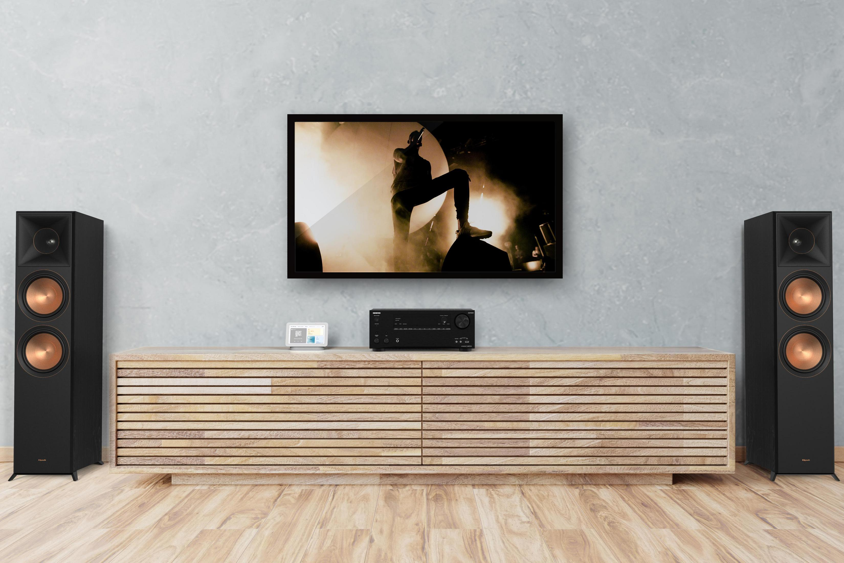 Ustawienie w salonie z głośnikami, telewizorem i sprzętem audio na drewnianej szafce.