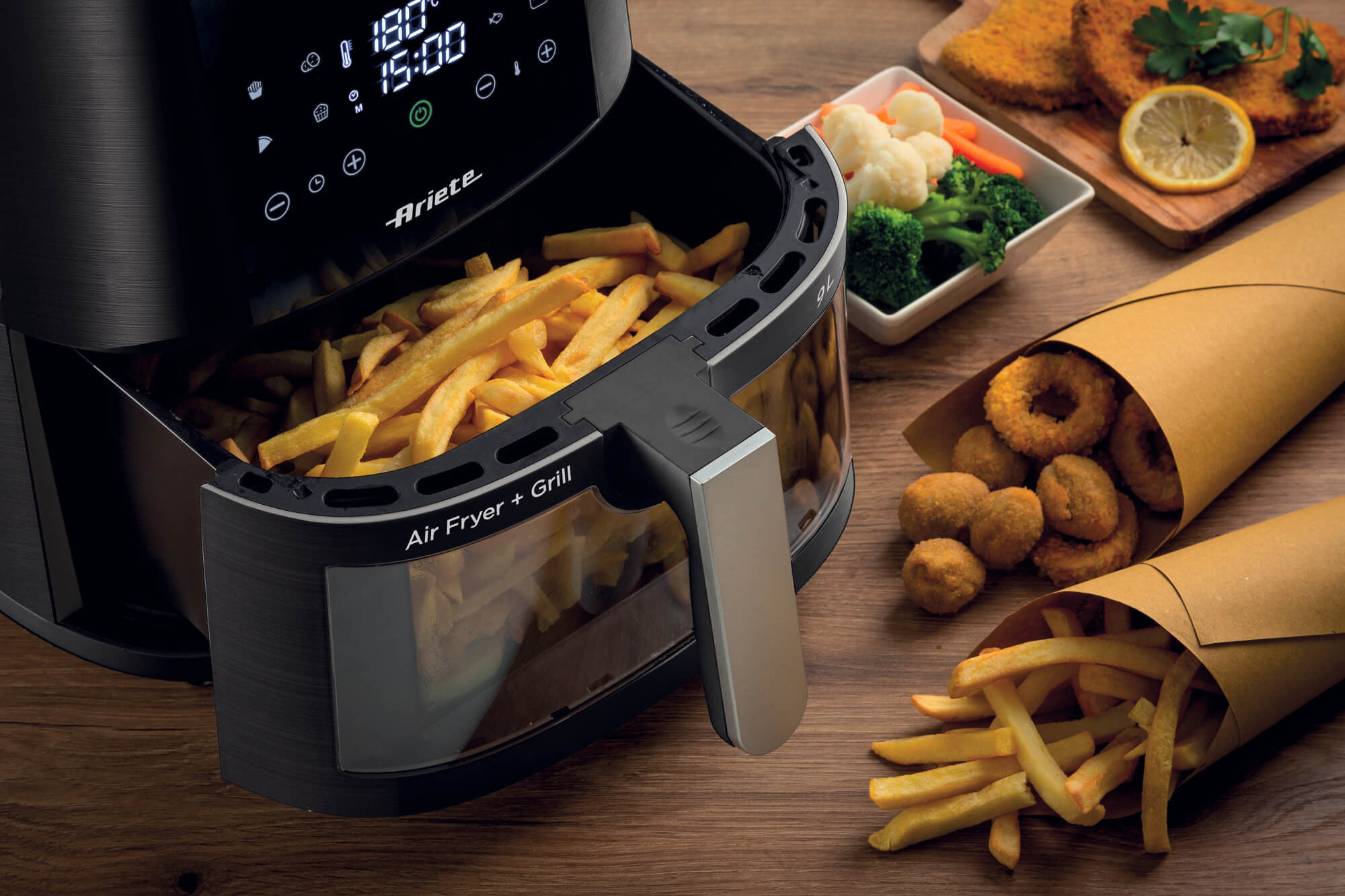 Heißluftfritteuse mit Pommes und anderen frittierten Speisen, auf einem Holztisch.