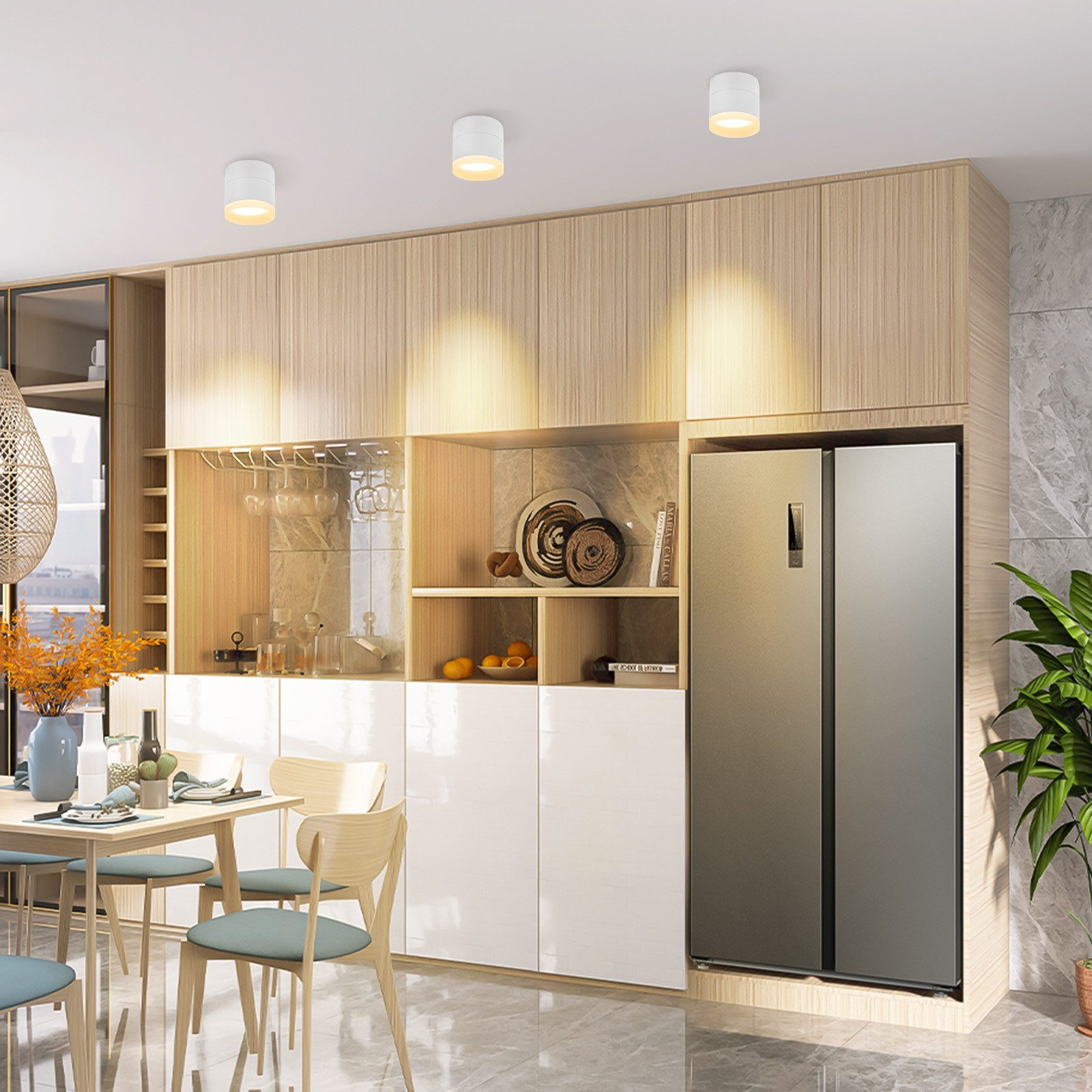 Cucina moderna con luci a soffitto, armadi, un frigorifero e tavolo da pranzo con sedie.