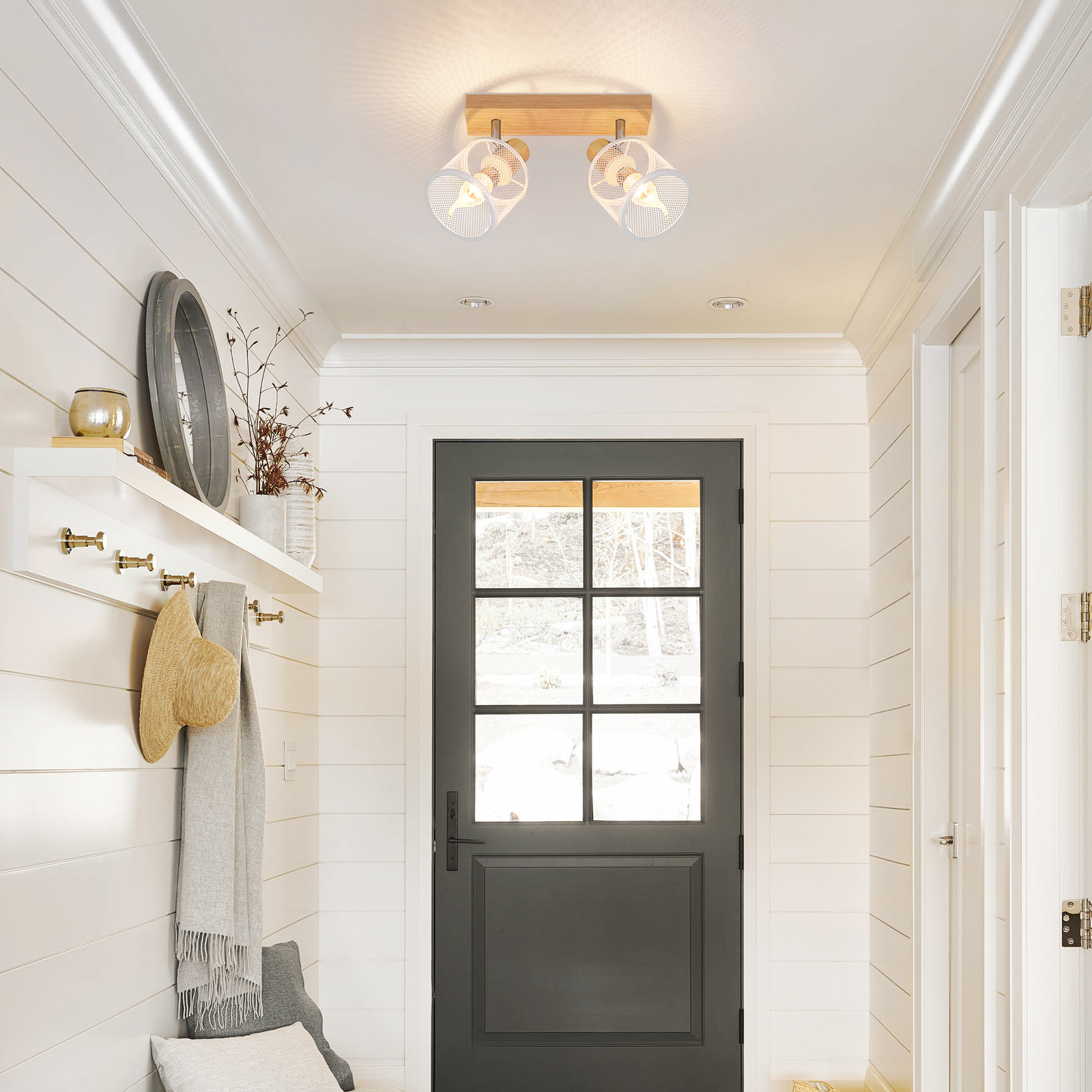 Corridoio con pannelli bianchi, una porta nera e un'illuminazione a soffitto.