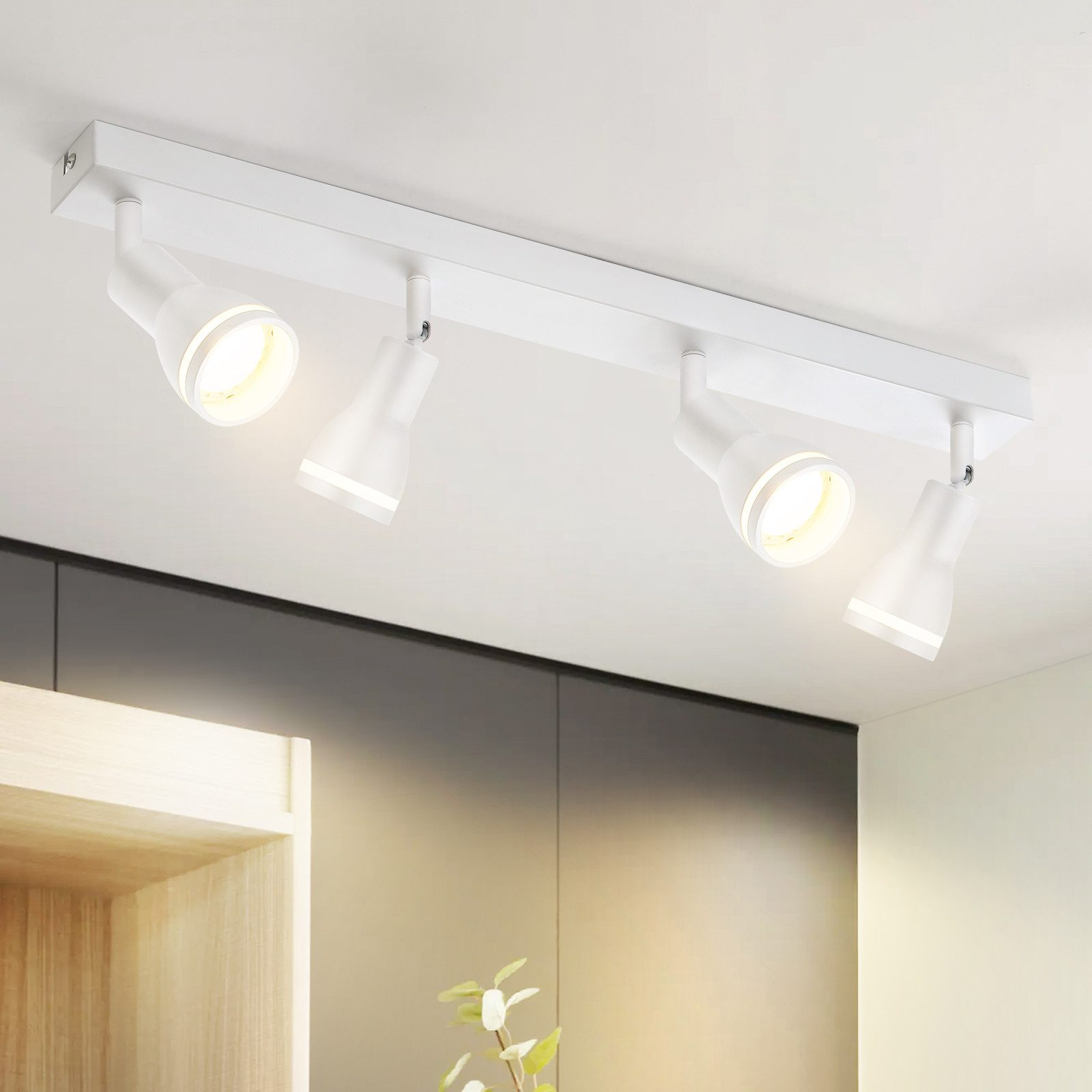 Illuminazione a binario bianca montata a soffitto con quattro faretti che illuminano una stanza.