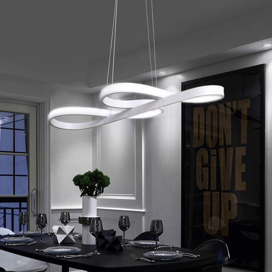 Nowoczesna biała lampa wisząca nad czarnym stołem jadalnym. Plakat mówi "DON'T GIVE UP". Czarne krzesła.