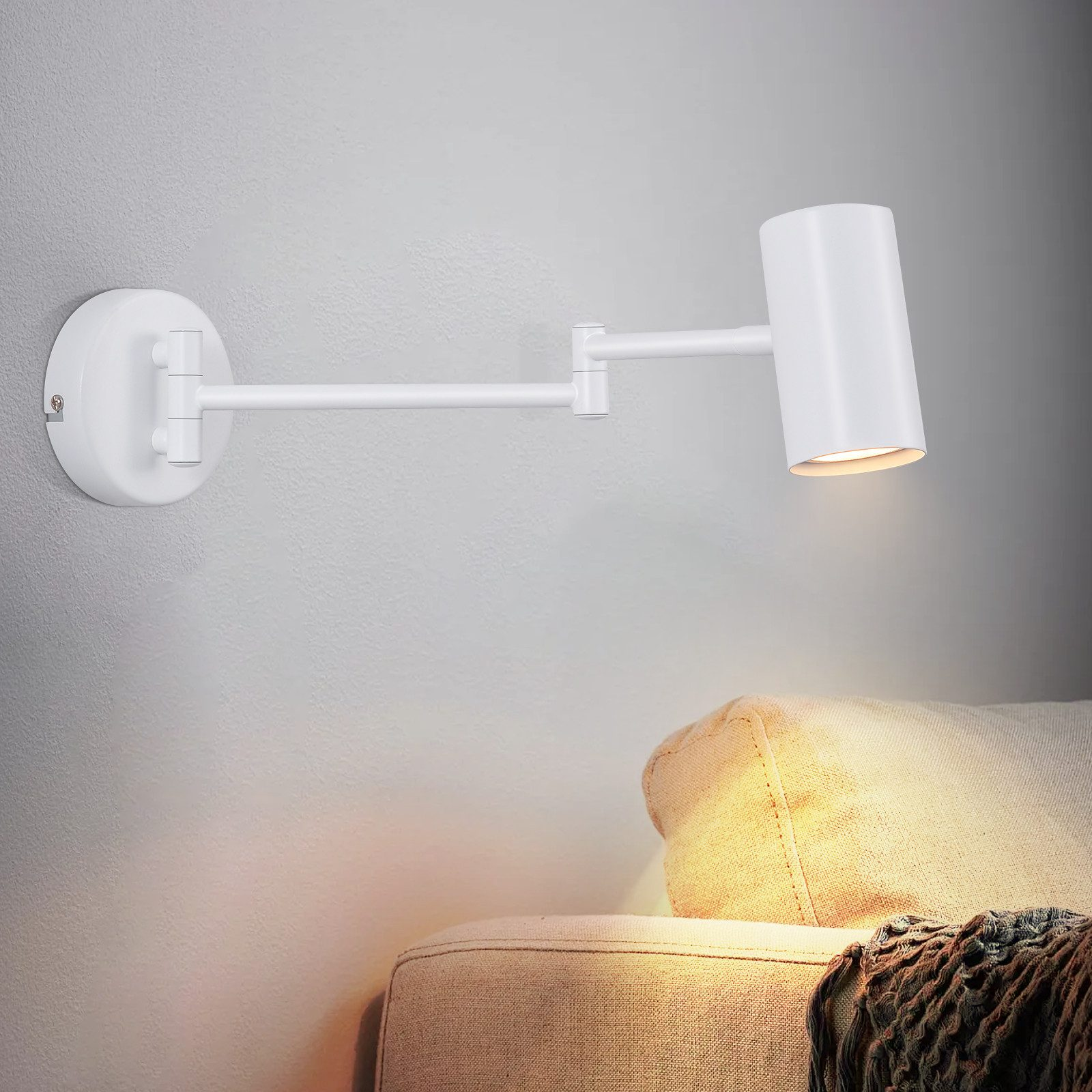 Lámpara blanca de pared ajustable. Está inclinada hacia el espectador.