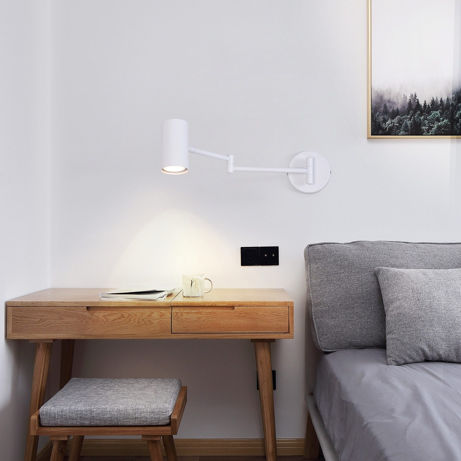 Una lámpara de pared ajustable blanca está montada en una pared blanca sobre un escritorio de madera.