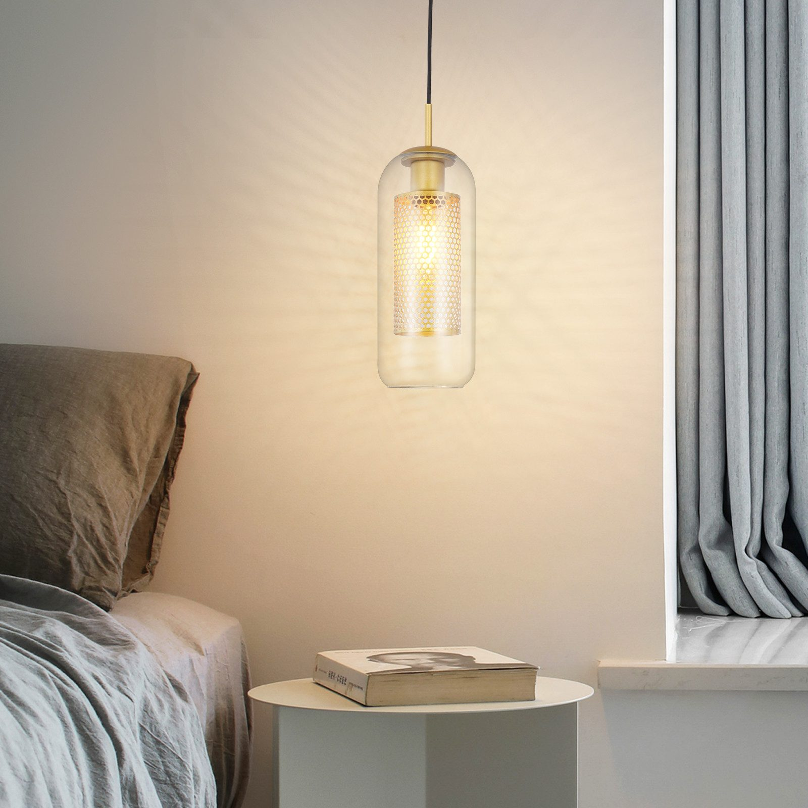 Lampada a sospensione con oro e vetro trasparente, con tavolo e libro.