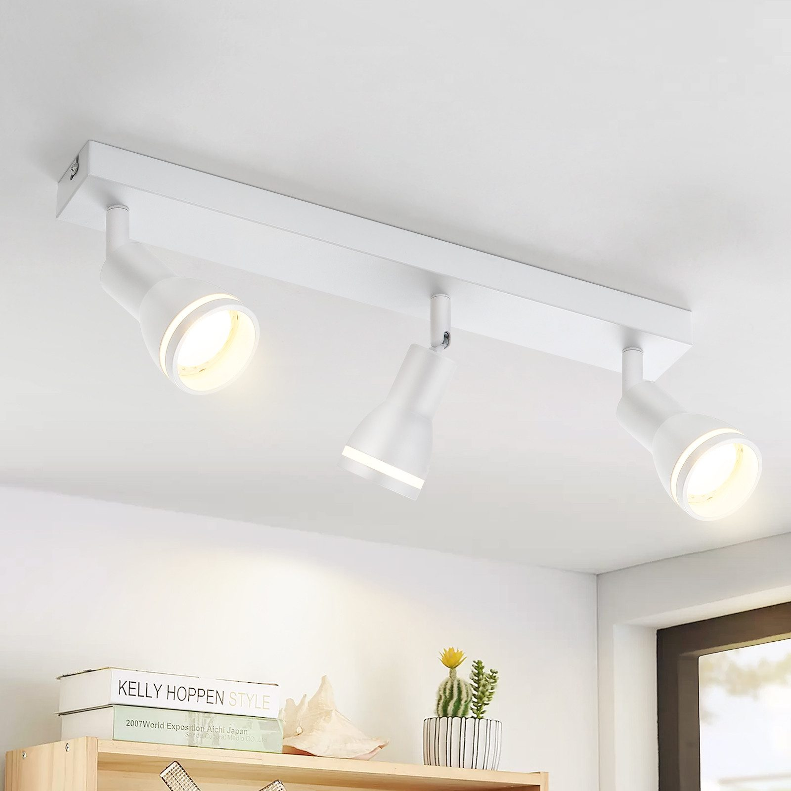 Tre faretti bianchi su una guida bianca, montati su un soffitto bianco, angolati.