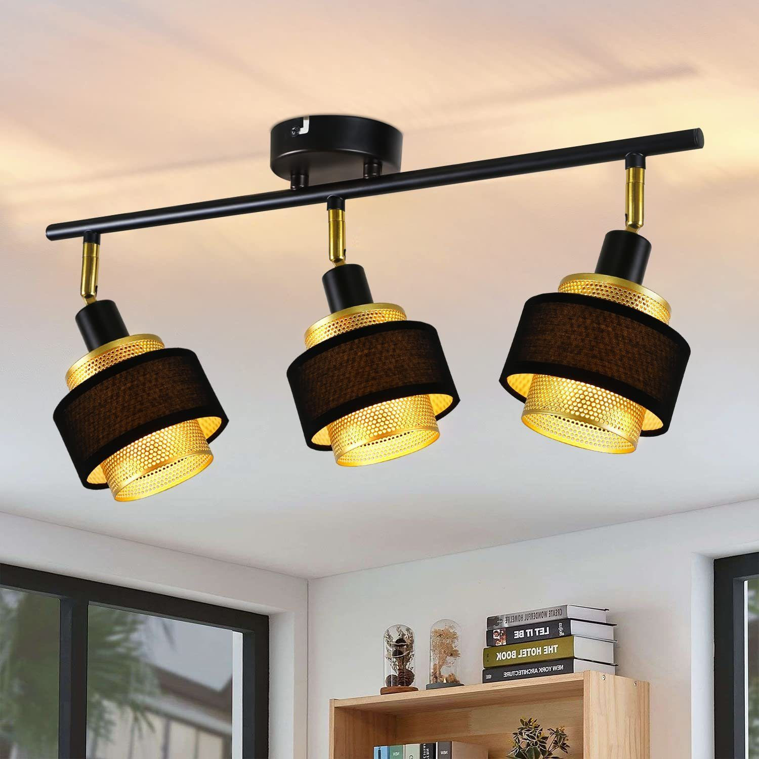 Tre faretti neri e dorati su una barra nera, montati su un soffitto bianco in un ambiente.