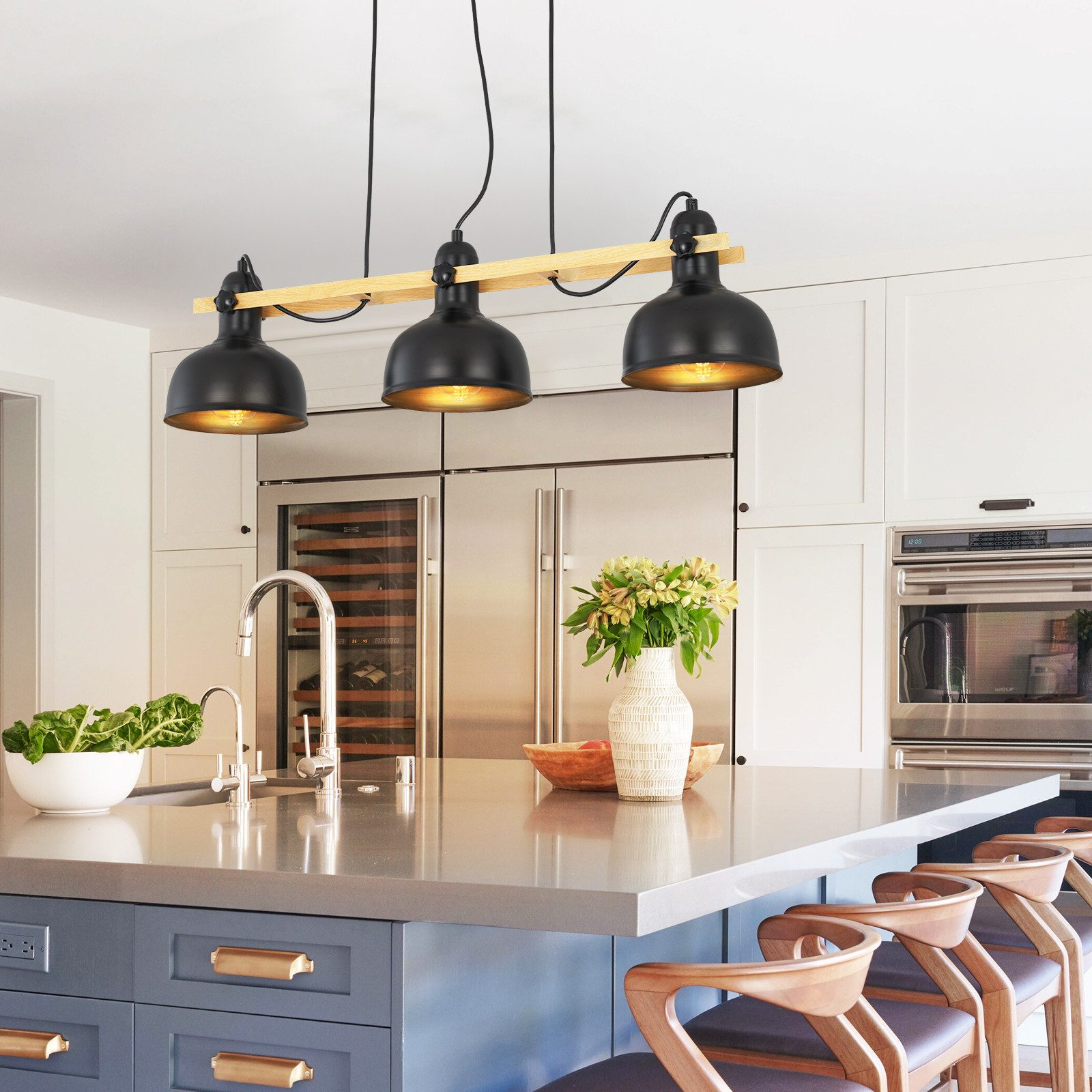 Kuchnia z czarnymi lampami wiszącymi nad wyspą, urządzeniami ze stali nierdzewnej i drewnianą podłogą.