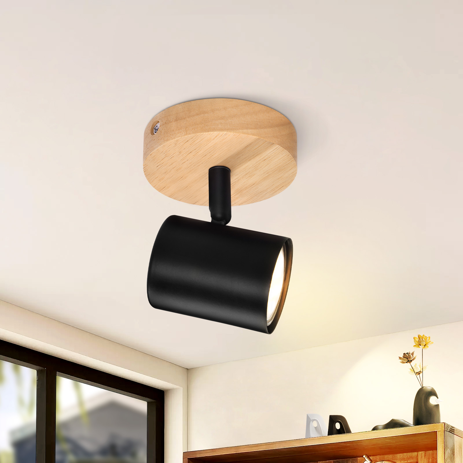Faretto nero montato su un fissaggio a soffitto in legno.