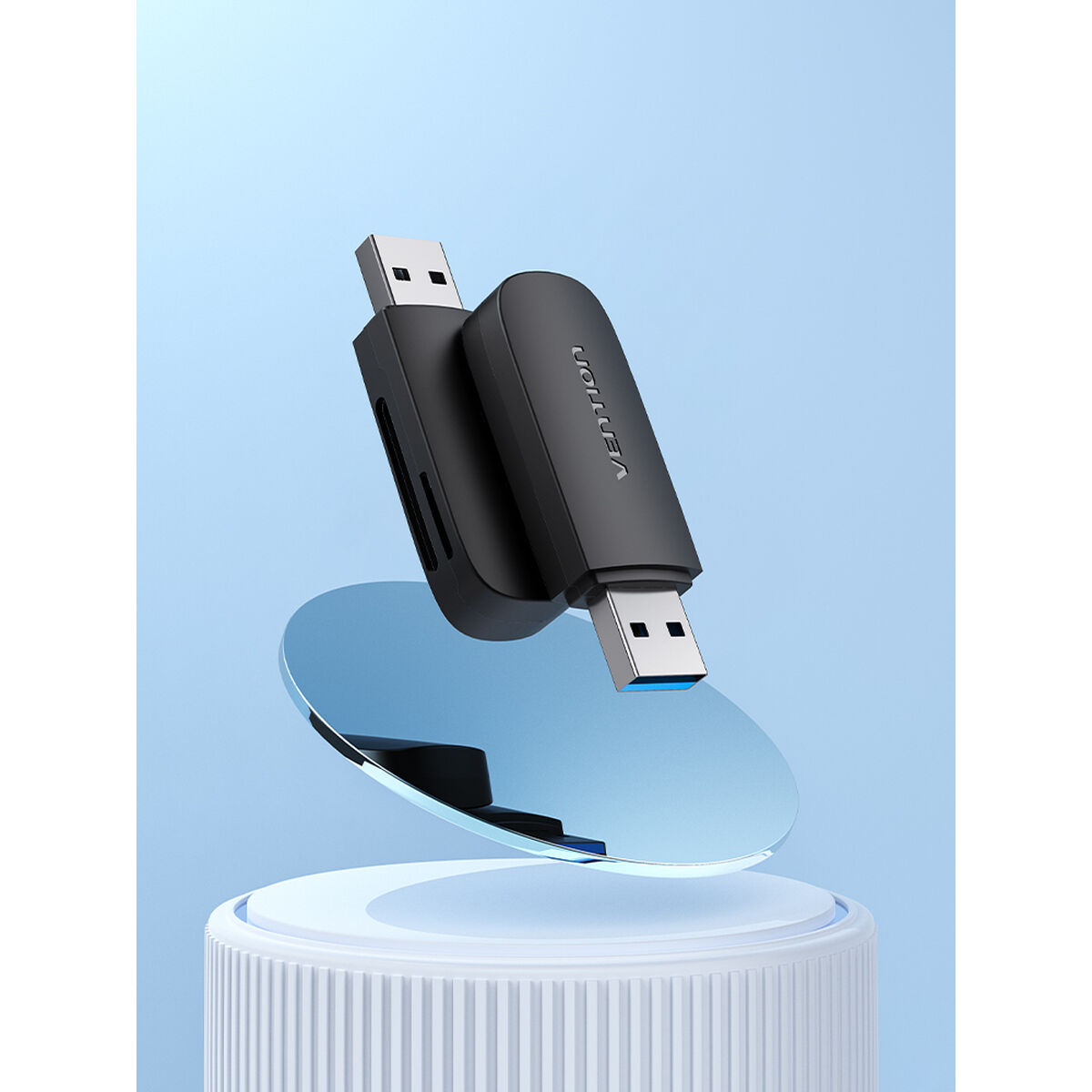 Czarny czytnik kart USB z niebieską podstawą, pochylony i unoszący się nad białą powierzchnią.