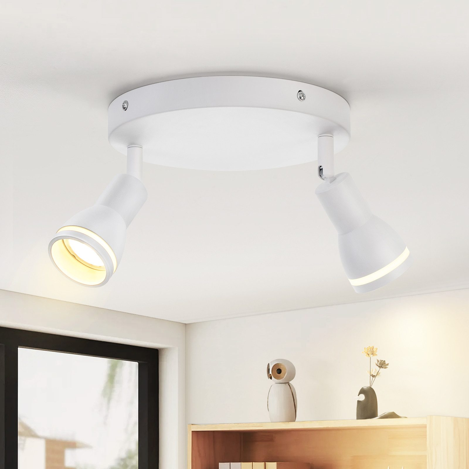 Due faretti bianchi su un soffitto bianco, che illuminano una mensola con oggetti decorativi.
