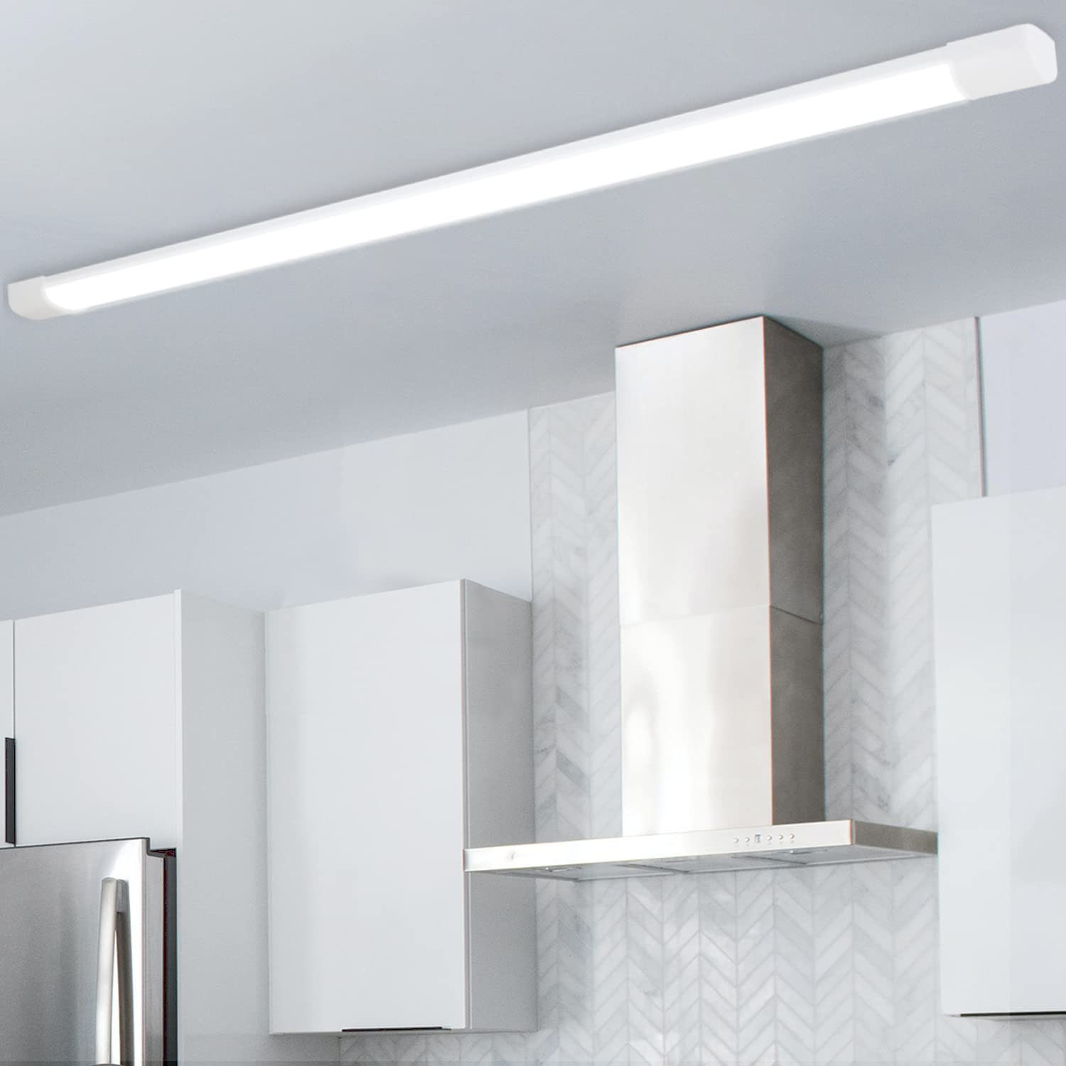 Luminaria LED blanca montada en un techo de cocina. Campana extractora de acero inoxidable visible.
